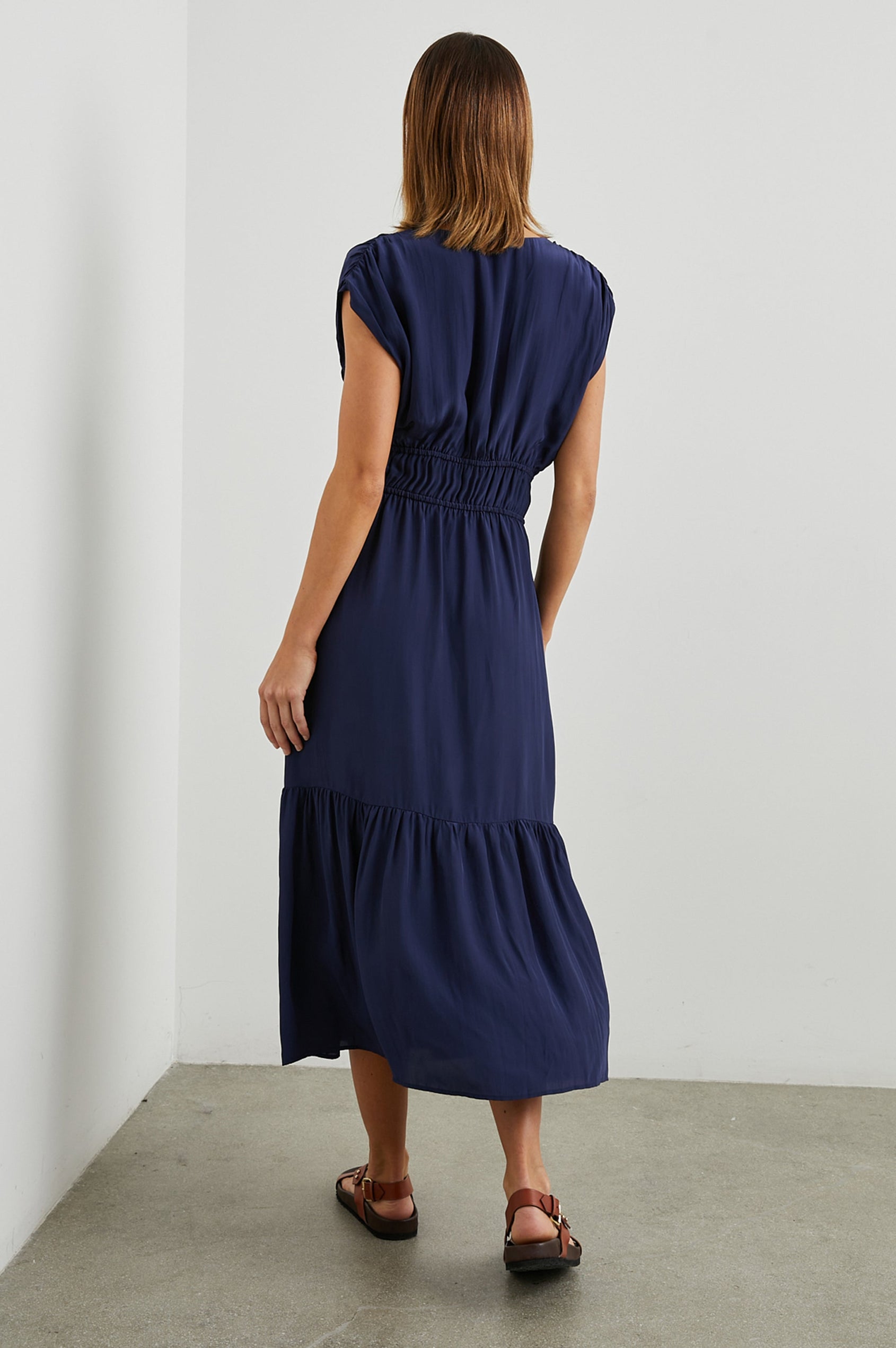 Aletta Short Sleeve Midi Dress with Cap Sleeves with Wide Arm Holes, Two Drawstrings at the Waist, a Deep V Neck, a Tiered Skirt and Ruching at the Front Yoke Seam and Shoulder Seam in Admiral Blue Colorway - Back Full Body View Featured on Model