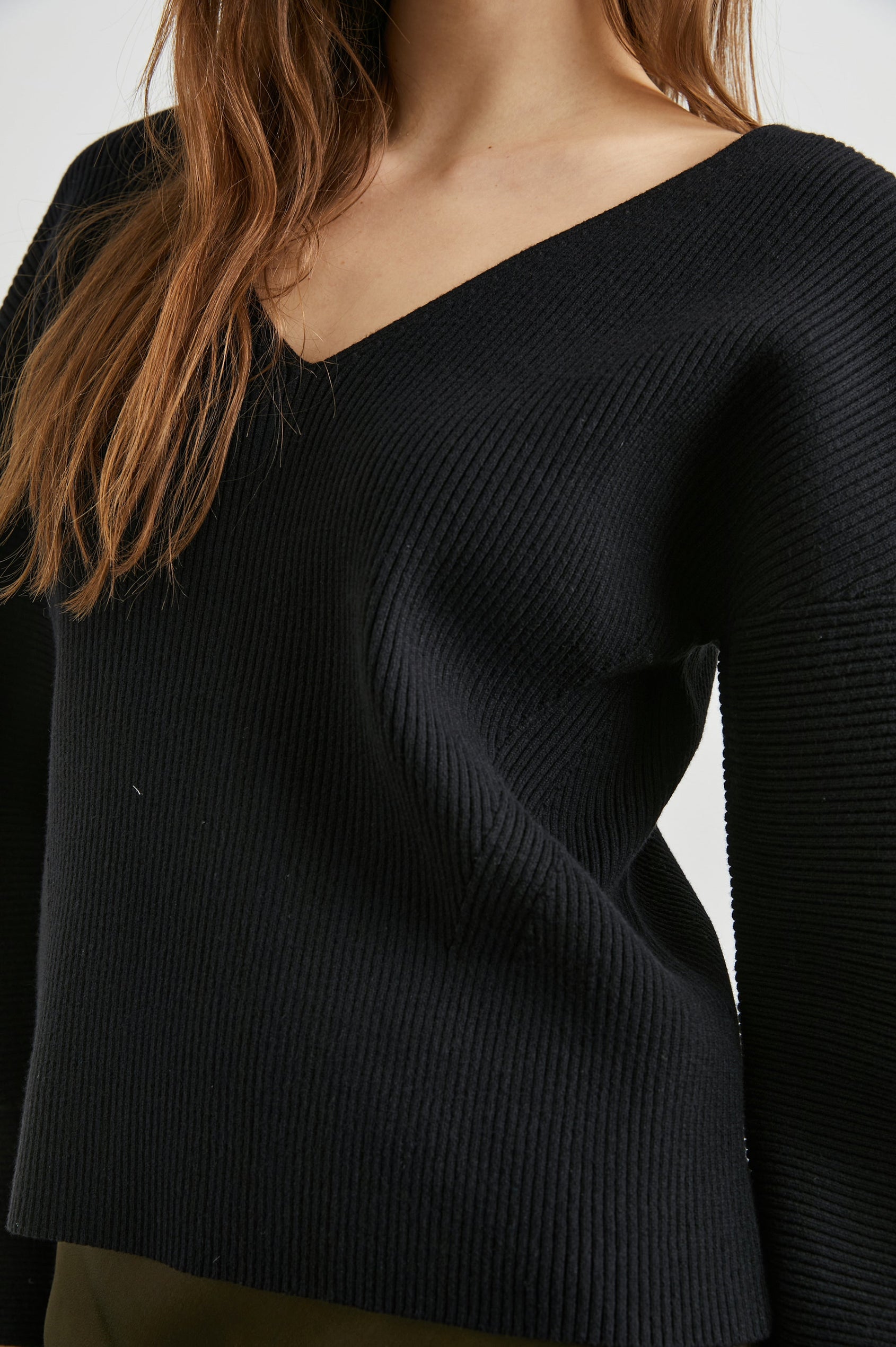 Alondra Ribbed Long-Sleeve Sweater with a Deep V Neck and Puff Sleeves in Black Colorway - Front View Featured on Model