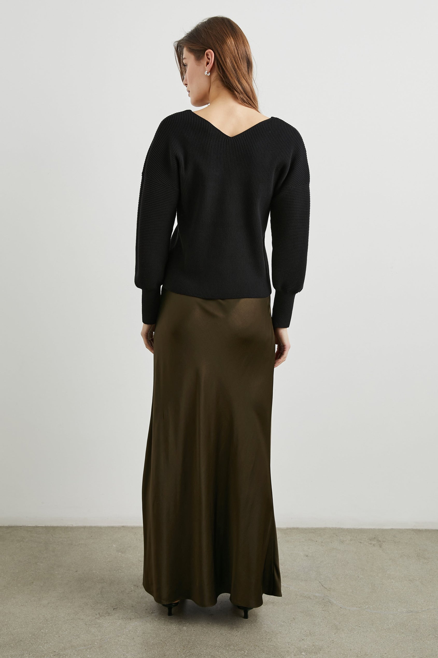 Alondra Ribbed Long-Sleeve Sweater with a Deep V Neck and Puff Sleeves in Black Colorway - Back Full Body View Featured on Model