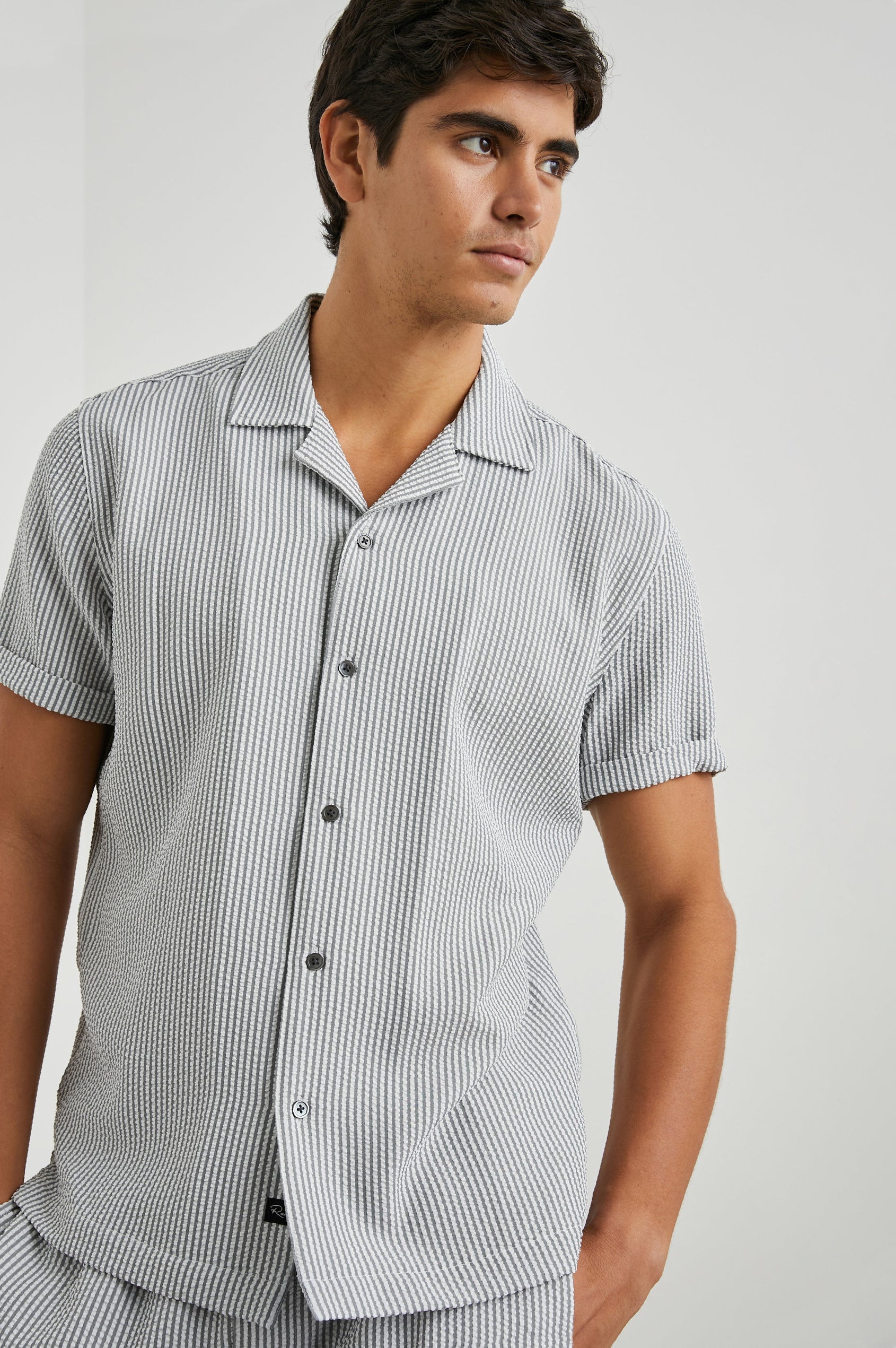 Amalfi Short-Sleeve Button Up in Faded Seersucker Colorway, Grey and white thin vertical stripes - Front View Featured on Model