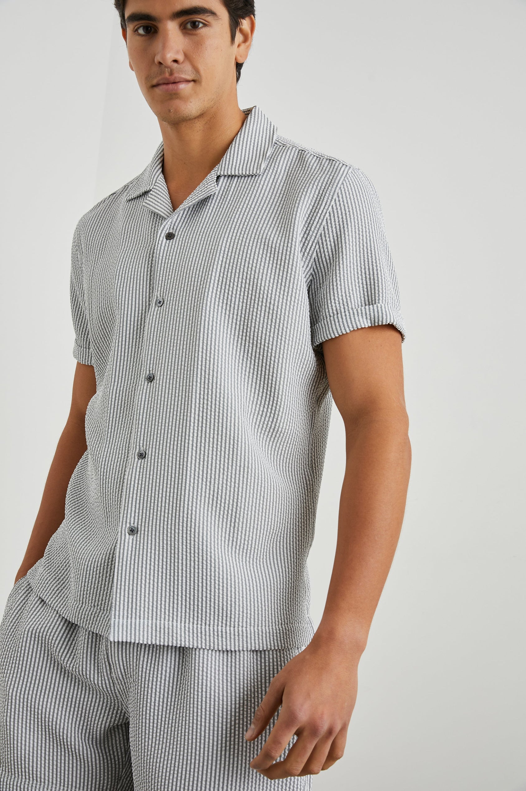 Amalfi Short-Sleeve Button Up in Faded Seersucker Colorway, Grey and white thin vertical stripes - Front View Featured on Model