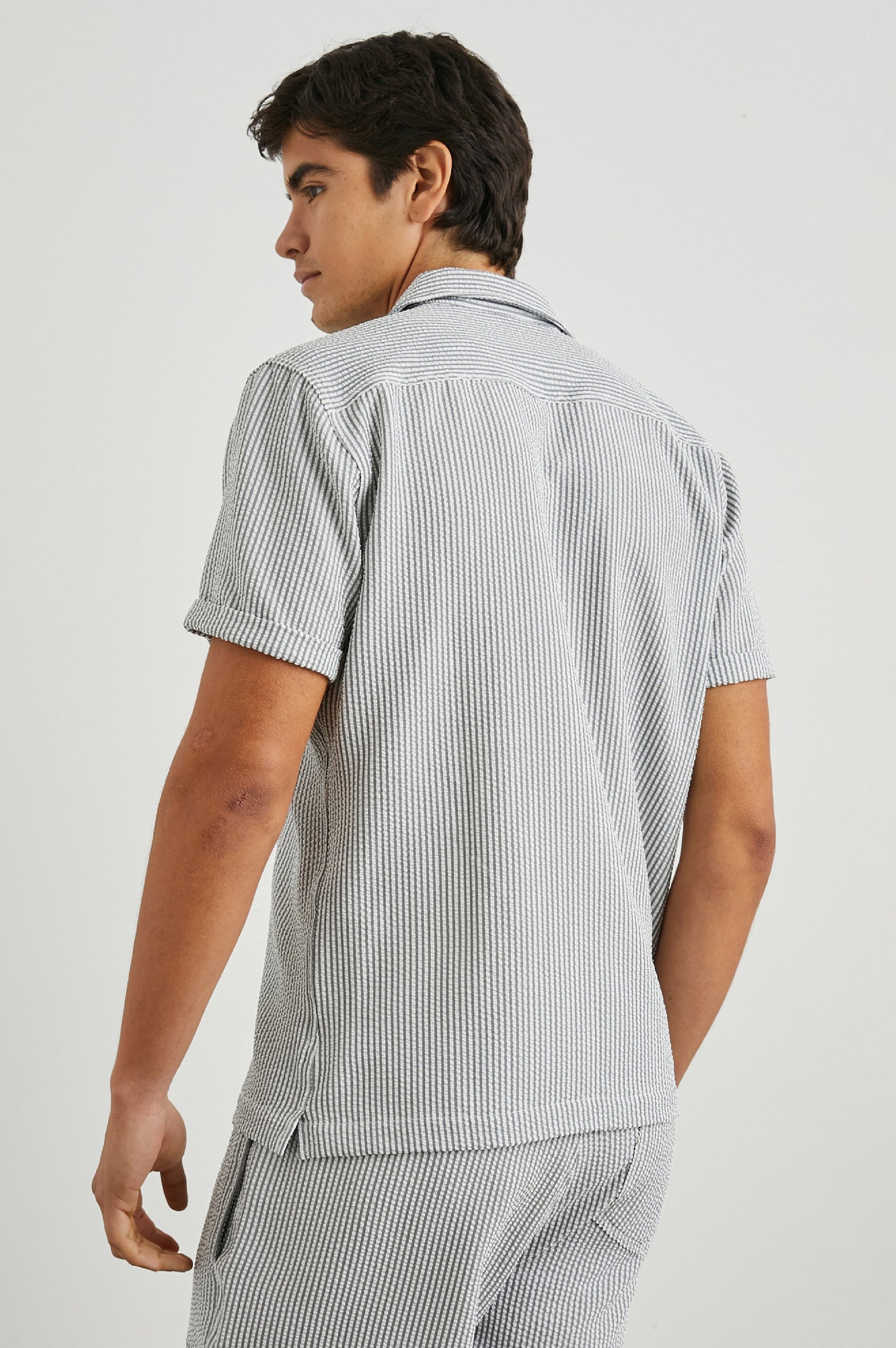 Amalfi Short-Sleeve Button Up in Faded Seersucker Colorway, Grey and white thin vertical stripes - Back View Featured on Model