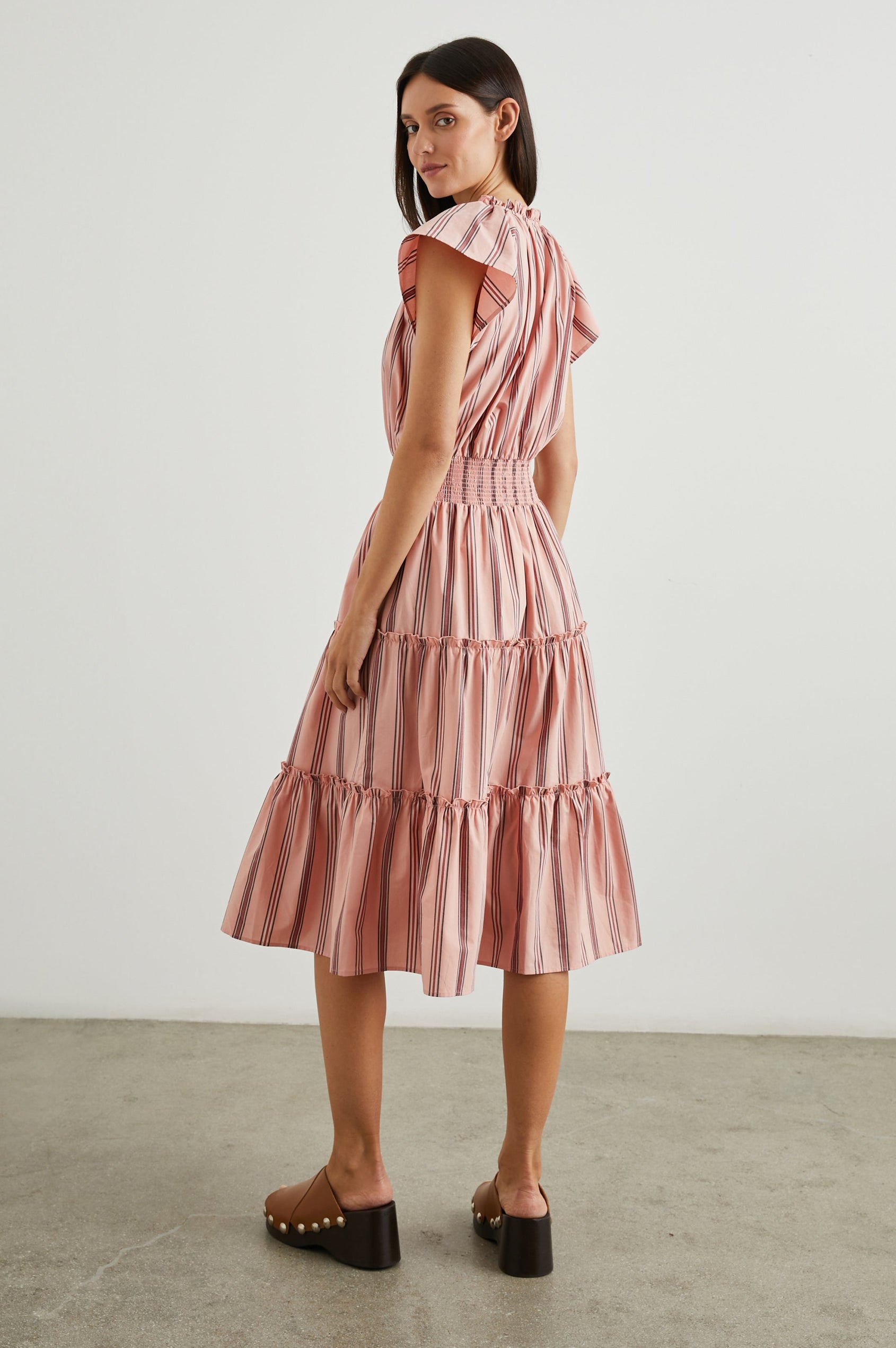 Amellia Short-Sleeve Midi Dress with Smocked Waist and Collar, V Neck, and a Tiered Skirt in Coral Navy Stripe Colorway, Vertical Coral and Navy Stripes on Peach - Back Full Body View Featured on Model