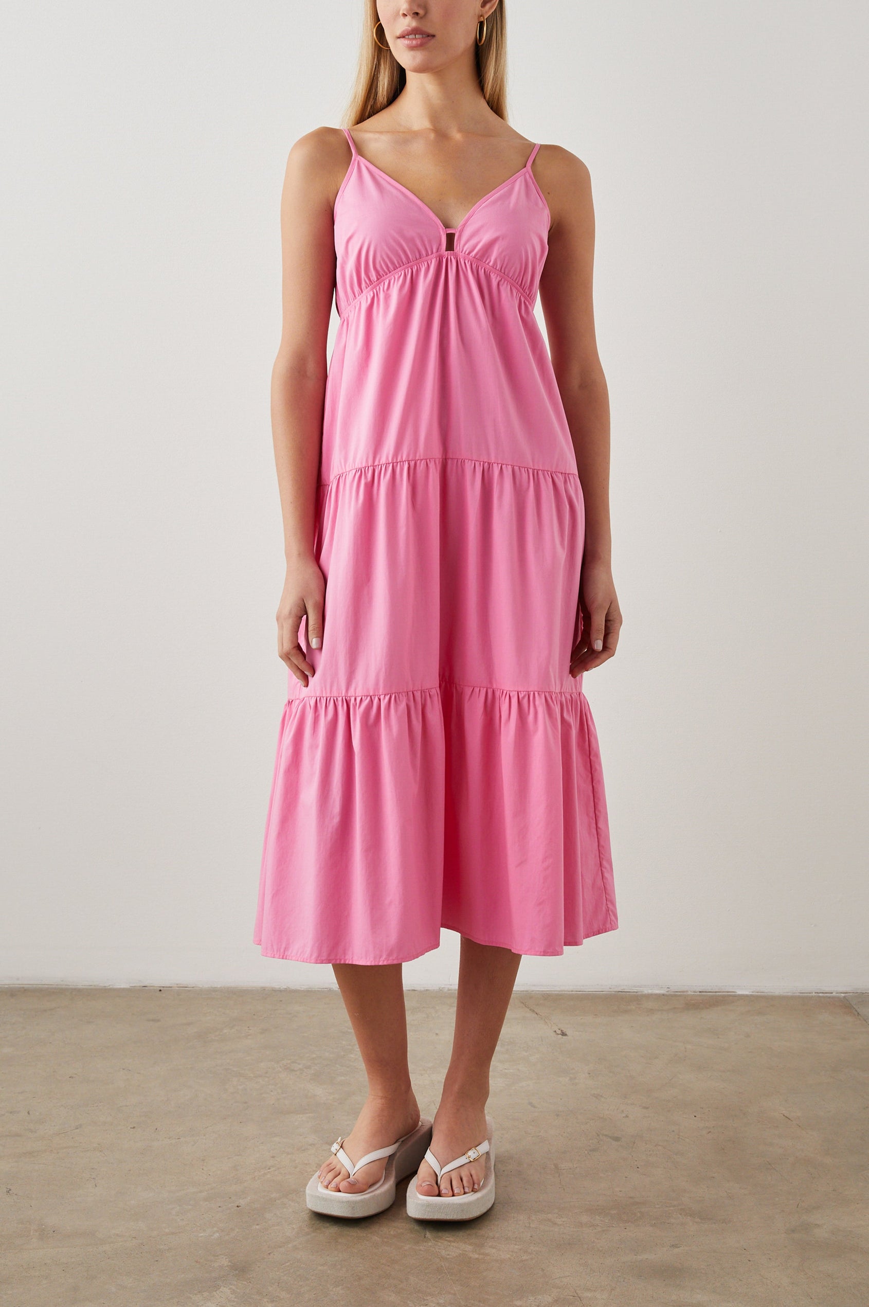 Avril Sleeveless, Tiered Midi Dress with Adjustable Spaghetti Straps, a V Neck with a Cutout and Light Ruching at Each Tier Seam in Hot Pink Colorway - Front Full Body View Featured on Model