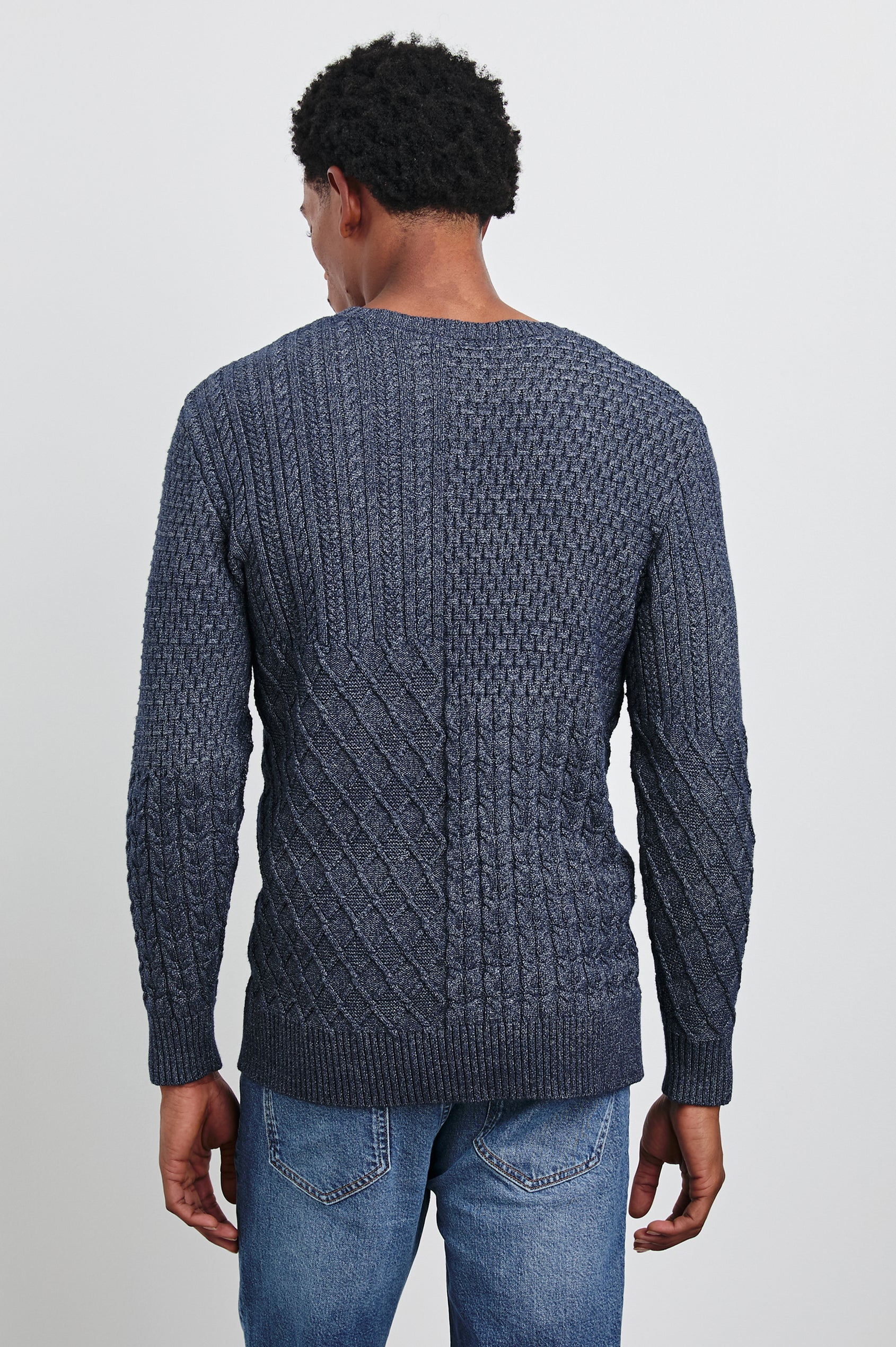 Biarritz Long-Sleeve Sweater with a Crew Neck and Patches of Different Cable Knits in Multi Weave Indigo Colorway - Back View Featured on Model