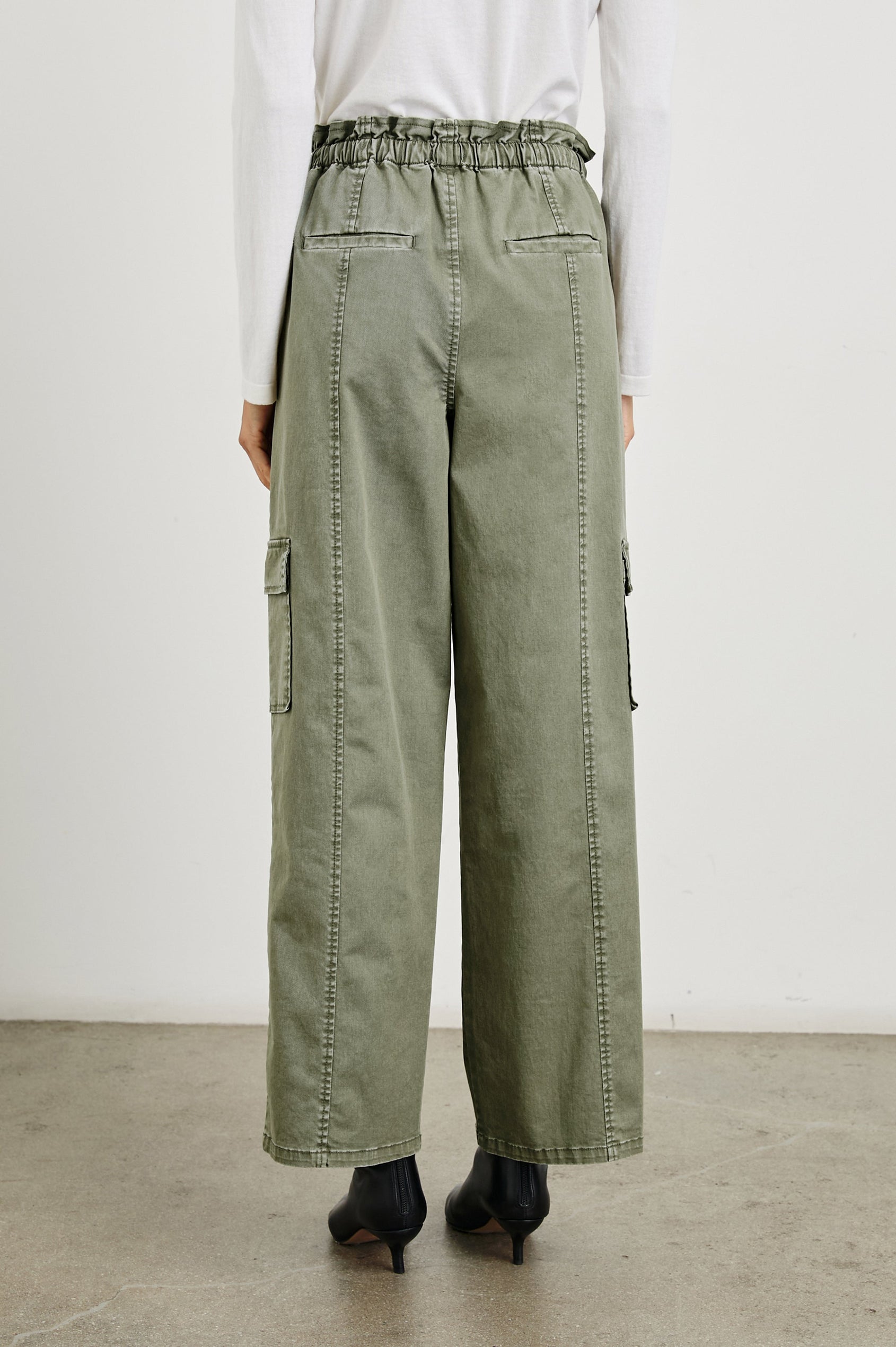 Bodie Pants with a Drawstring Waist, Front and Back Center Vertical Leg Seams, Two Front Pockets, Two Flap Side Pockets and Two Back Welt Pockets in Dark Olive Colorway - Back View Featured on Model