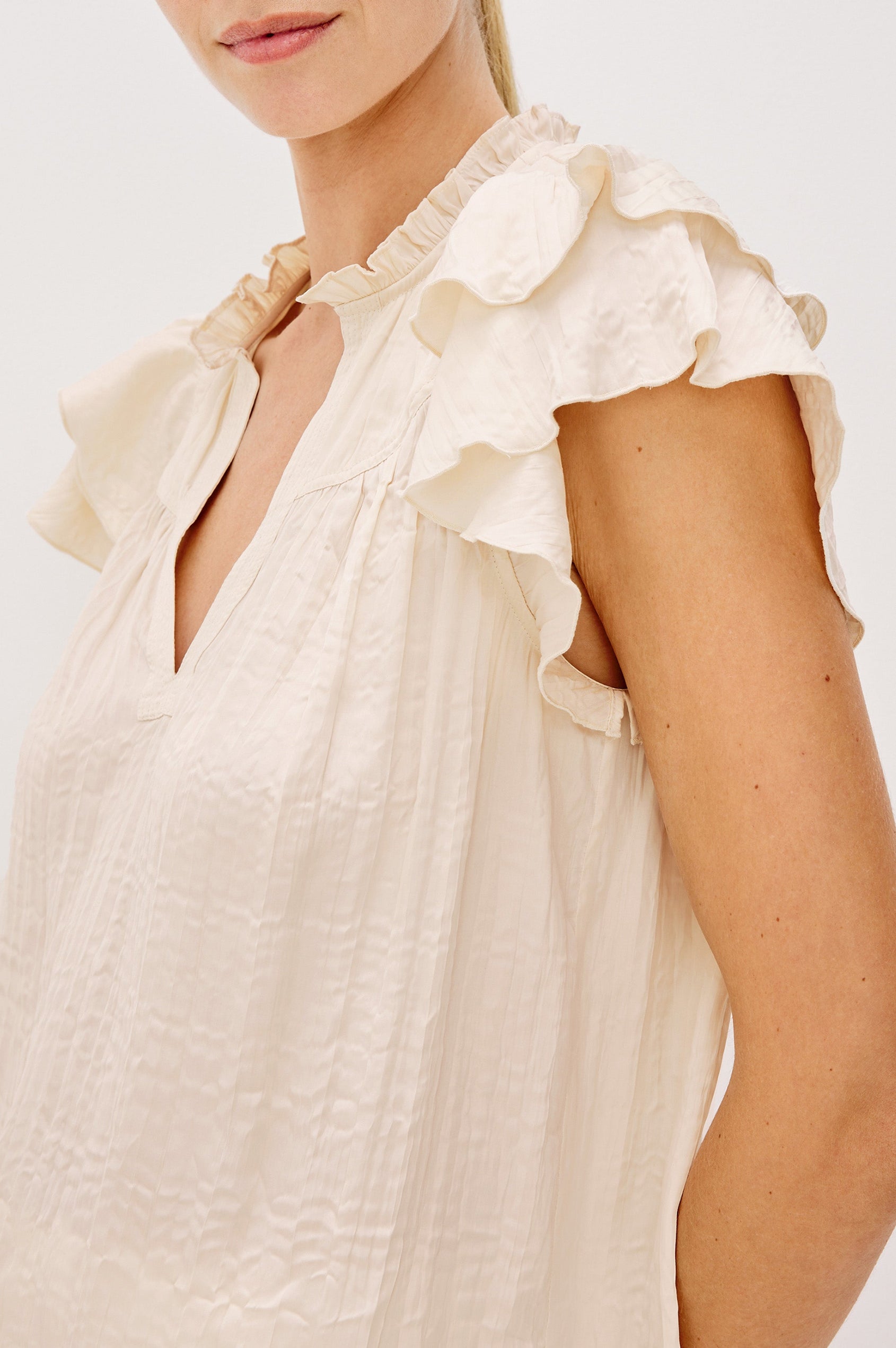 Calista V-Neck Ruffle Sleeve Blouse with a Ruffled Neckline and Gathered Front Yoke in Ivory Colorway. Side Detail View Shown on Model.