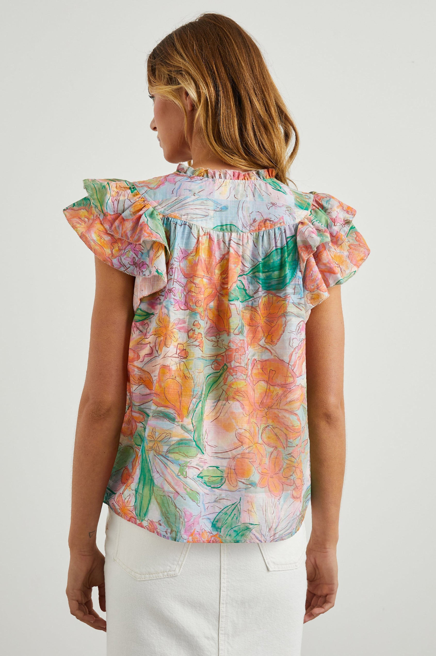Calista Short Sleeve Top with Double Layer Flutter Sleeves, a V Neck with a Placket, a Ruffled Collar, and Light Ruching Along the Yoke in Tropics Colorway, Floral Print in Oranges, Greens and Blue - Back View Featured on Model