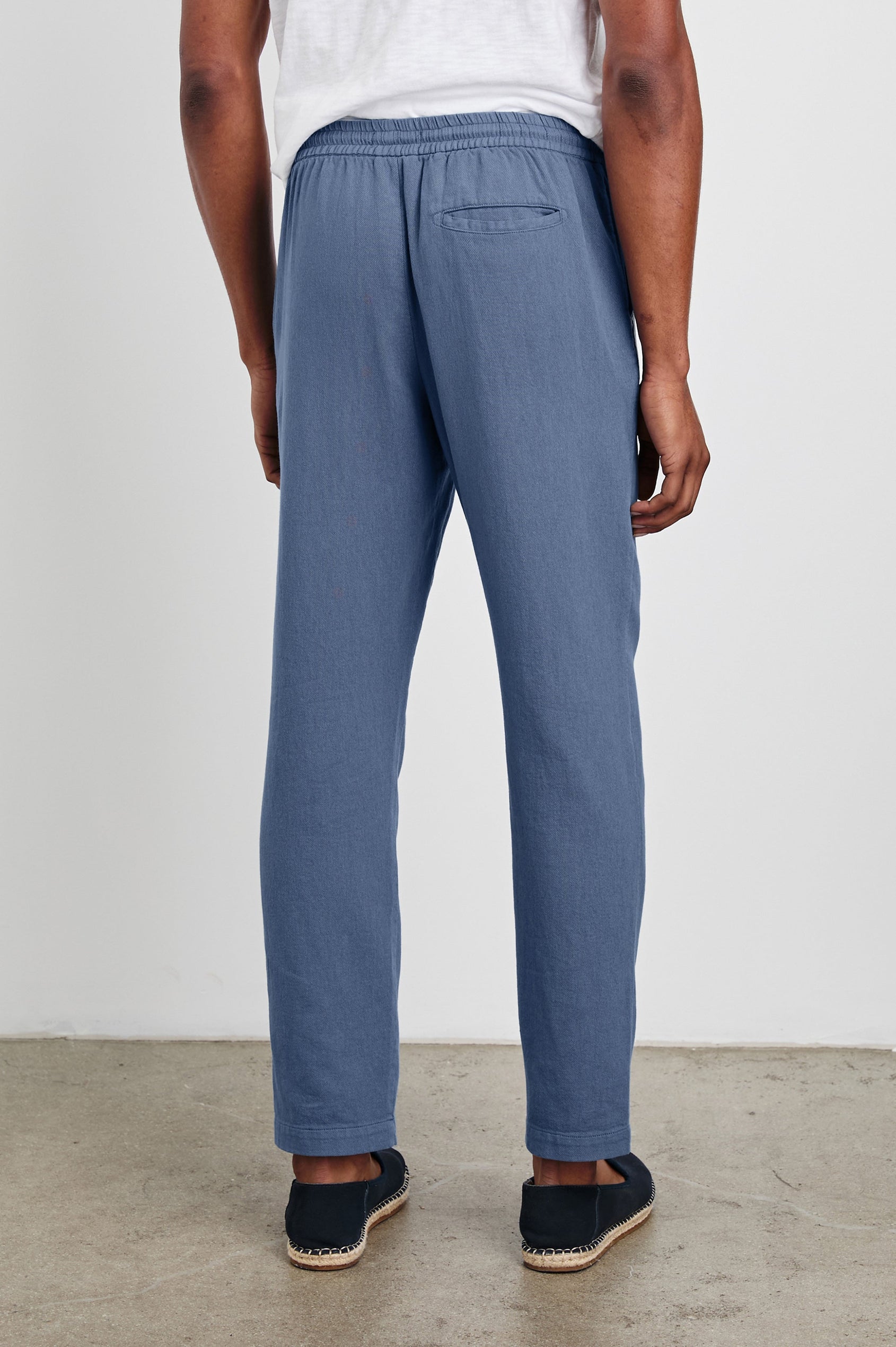 Callum Pants with a Drawstring Waist, Two Front Pockets and a Back Patch Pocket in Washed Blue Colorway - Back View Featured on Model