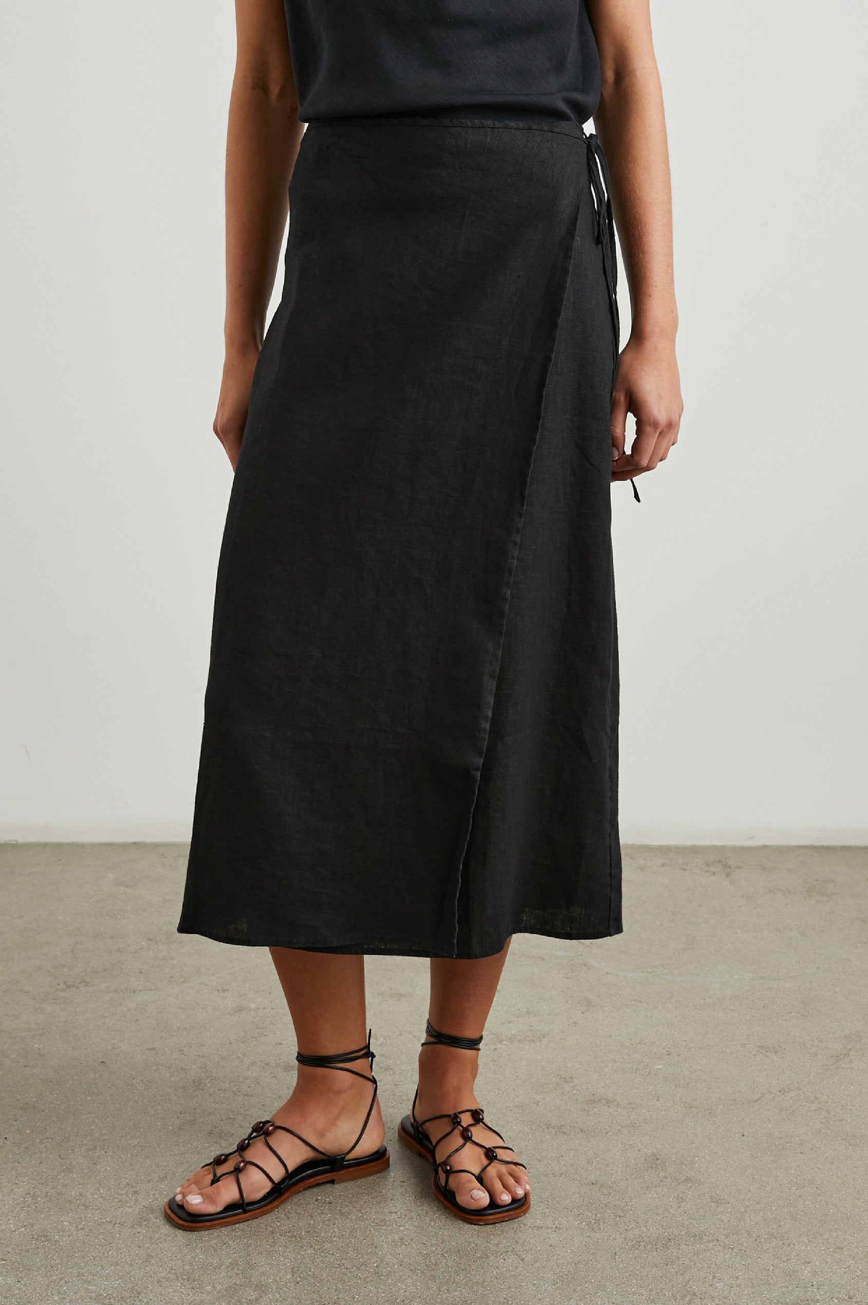 Carly Midi Wrap Skirt With a Side Tie in Black Colorway - Front View Featured on Model