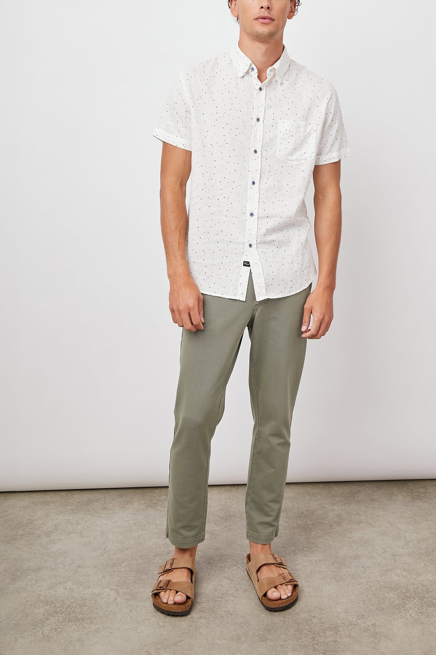 Carson Short Sleeve Button Up with a Chest Patch Pocket in Triangle Geo Colorway, Small Tan, Grey and Black Triangles on White - Front Full Body View Featured on Model