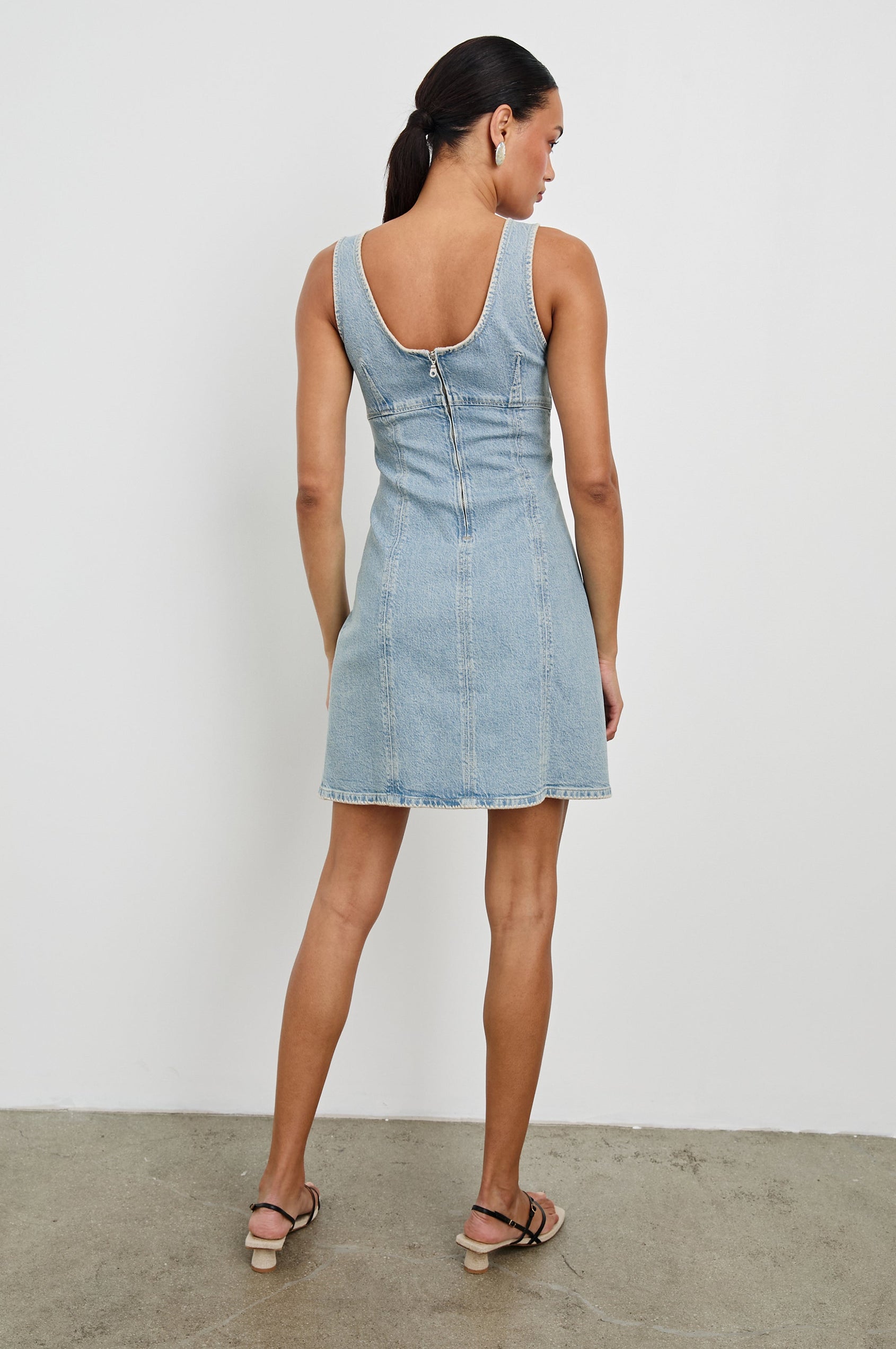 Cove Denim Tank Dress with a Scoop Neck, Empire Bust, Back Exposed Zipper Closure, A-line and Above-Knee Length in Capri Colorway. Full Body Back View Shown on Model.
