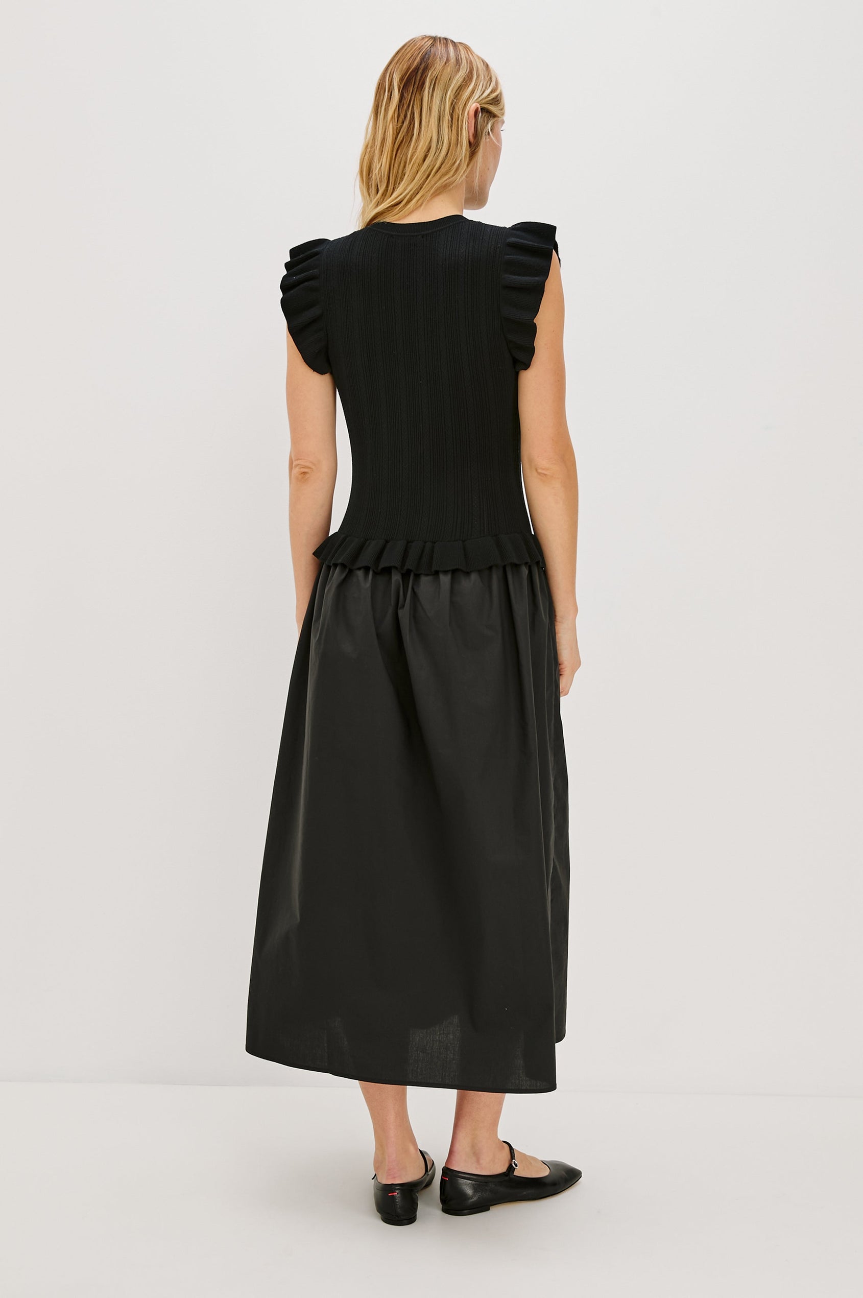 Deirdre, a maxi dress with a fitted fine-gauge knit bodice and flutter sleeves. The dress transitions at the waist into a full cotton poplin skirt, creating a soft, mixed-fabric silhouette. Back View featured on Model.