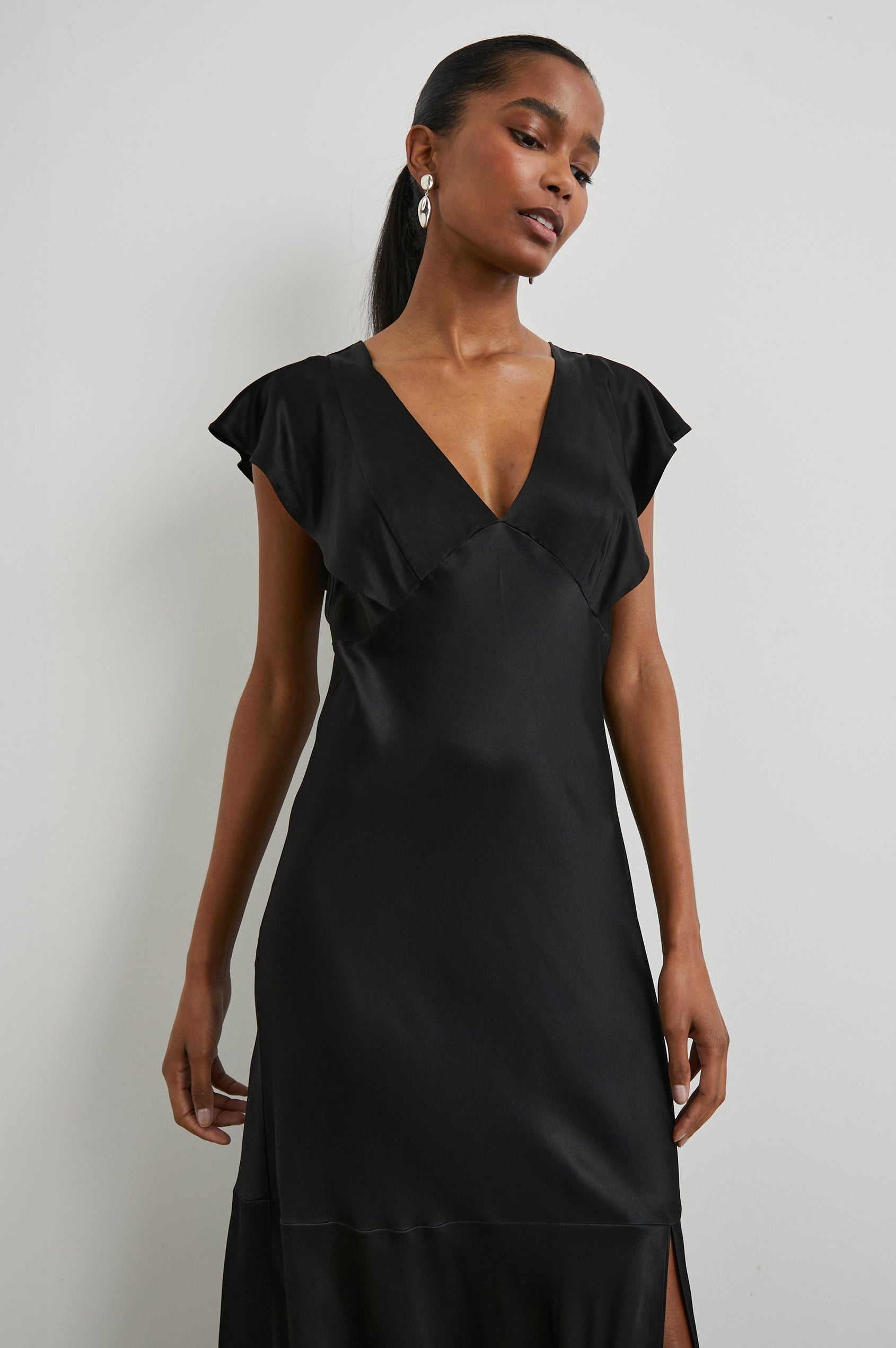 Dina Short-Sleeve Midi Dress with a Deep V Neck, Flutter Sleeves, and a Thigh Side Slit in Black Colorway - Front View Featured on Model