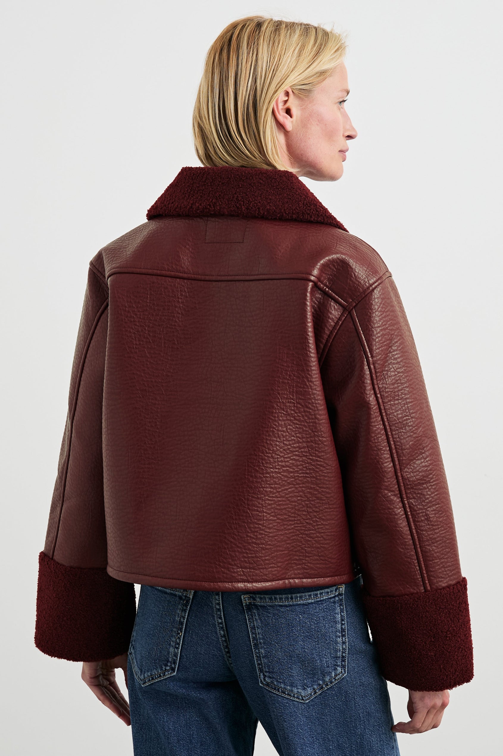 Dria Jacket with Button Closure, Two Front Patch Pockets and Faux Shearling at the Pockets, Cuffs, Collar and Opening in Maroon Shearling Colorway, Back View Featured on Model