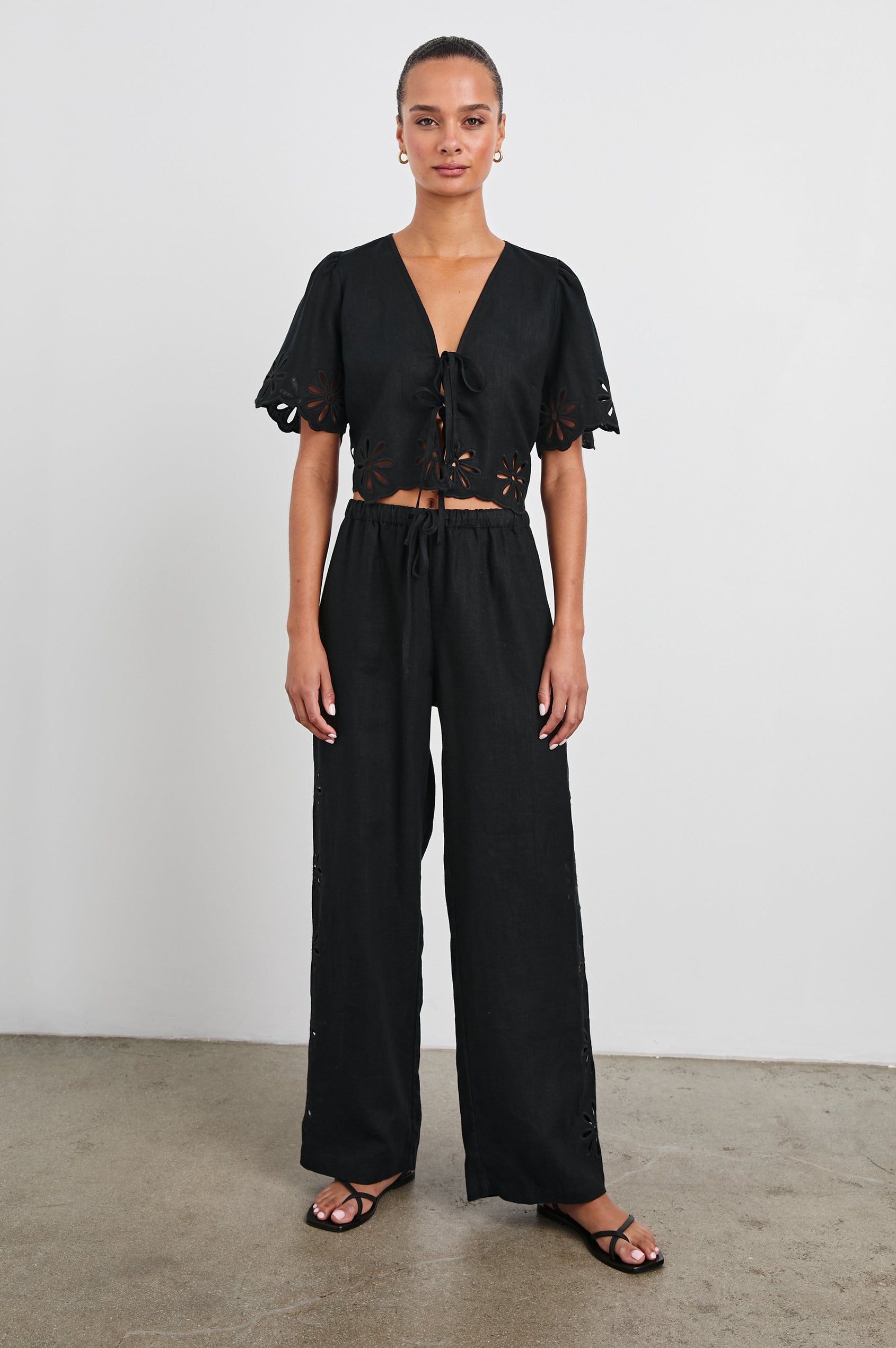 Emmie Pants with a Drawstring Waist and Two Front Pockets in Black Eyelet Colorway, with eyelets along the outer and inner sides - Front Full Body View Featured on Model