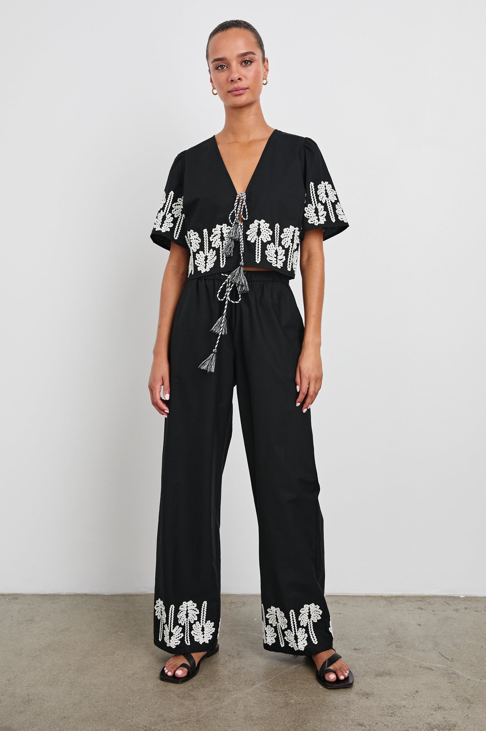 Emmie Pants with a Drawstring Waist and Two Front Pockets in Black Ivory Palm Trees Colorway, with white palm trees at the cuffs - Front Full Body View Featured on Model