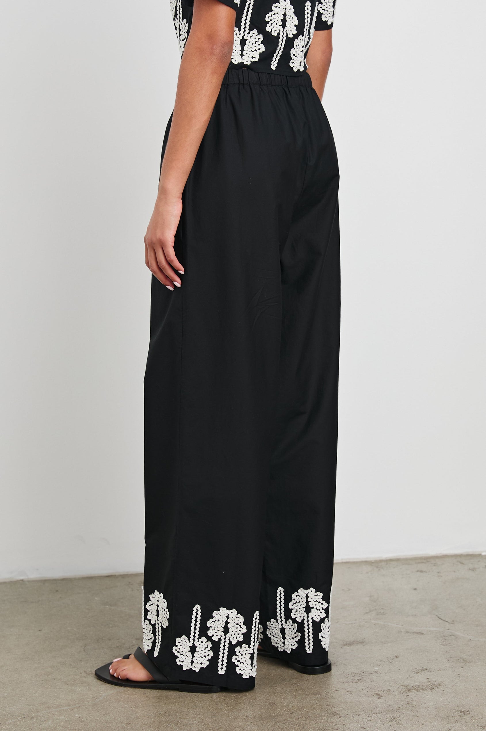 Emmie Pants with a Drawstring Waist and Two Front Pockets in Black Ivory Palm Trees Colorway, with white palm trees at the cuffs - Back View Featured on Model