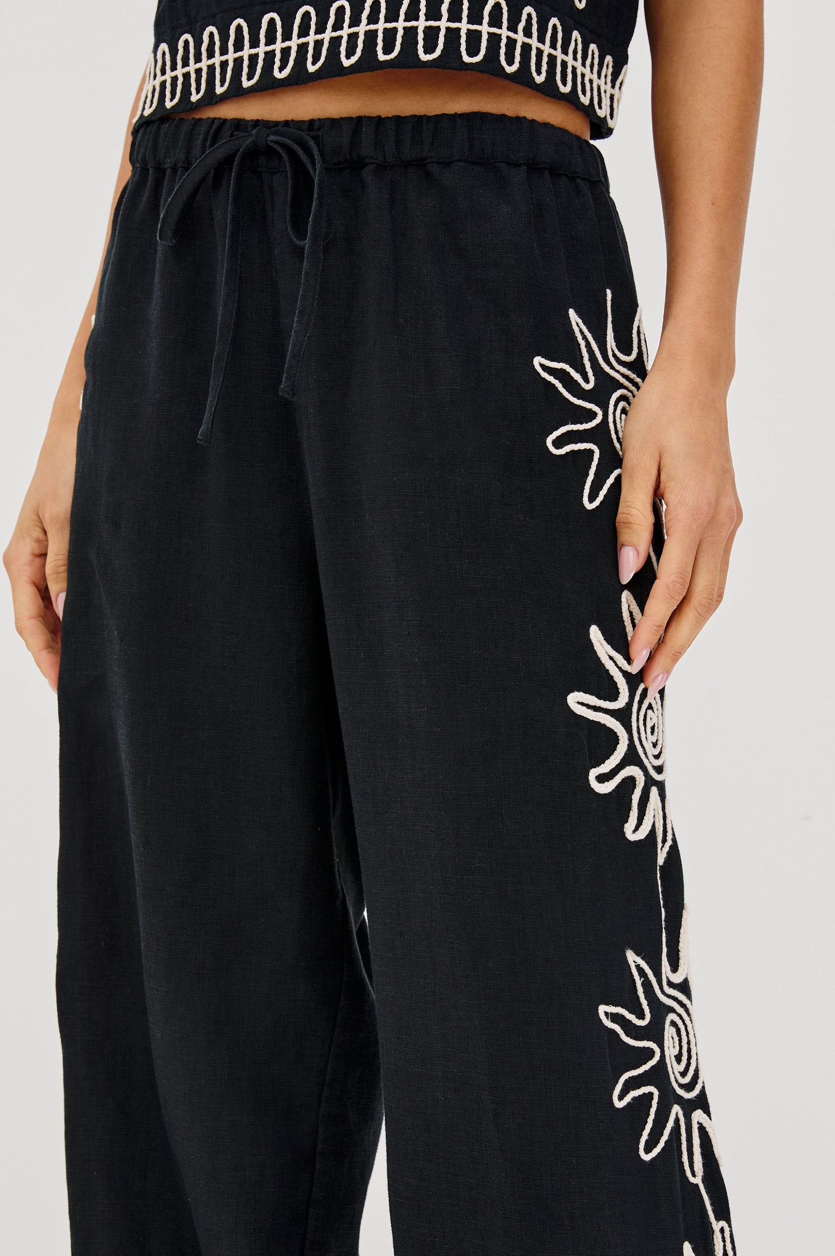 Emmie Straight Leg Pant with Adjustable Drawstring at Waist in White Contrast Sun Embroidery Colorway. Front Detailed View Shown on Model.