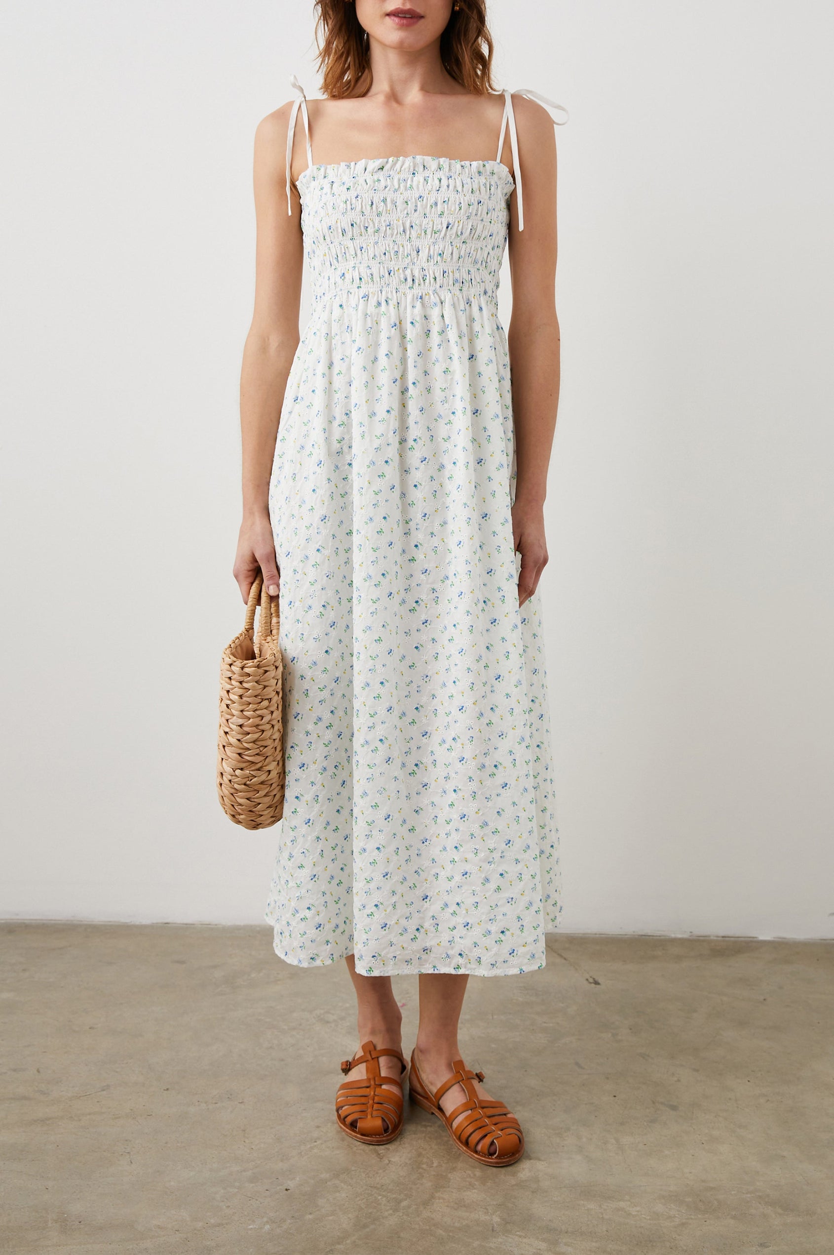 Faith Sleeveless Midi Dress with a Square Neckline, Tie Spaghetti Straps, Eyelets Across the Dress, and a Smocked Bodice in Bluebell Eyelet Colorway, Small Blue, Yellow and Green Flowers on White - Front Full Body View Featured on Model