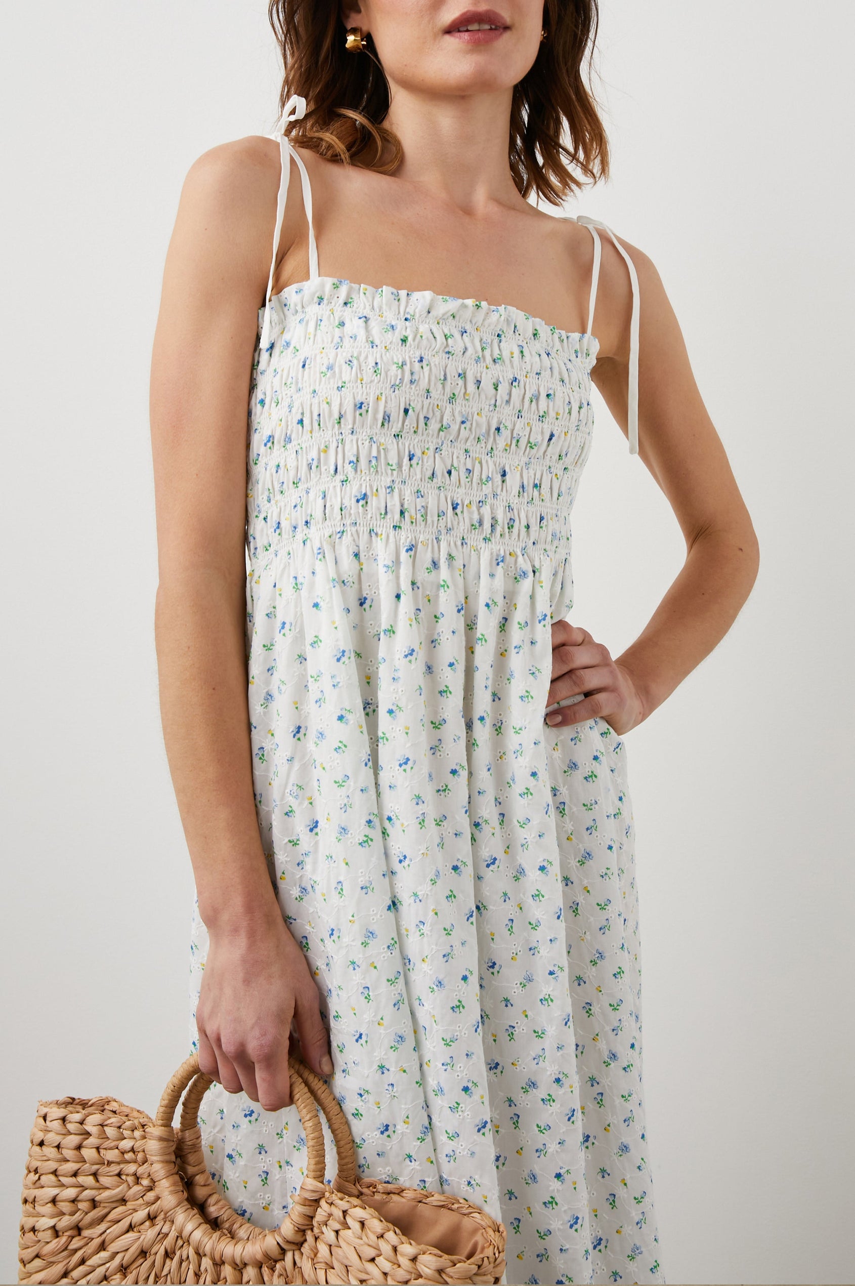 Faith Sleeveless Midi Dress with a Square Neckline, Tie Spaghetti Straps, Eyelets Across the Dress, and a Smocked Bodice in Bluebell Eyelet Colorway, Small Blue, Yellow and Green Flowers on White - Front View Featured on Model
