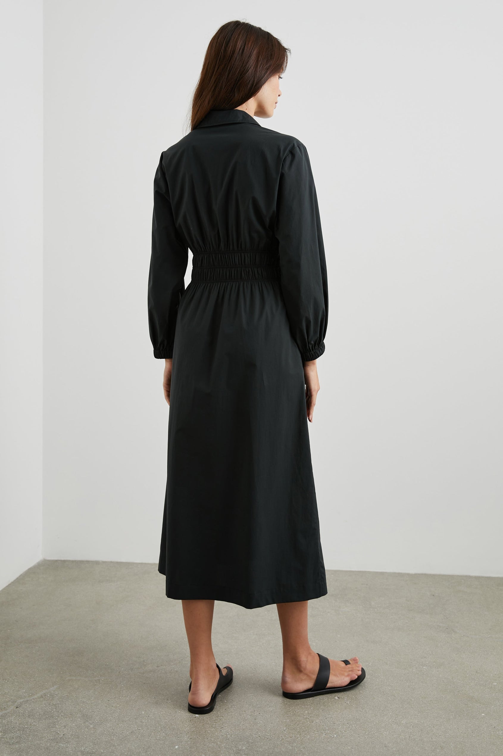 Fraya Long-Sleeve Midi Dress with a Concealed Button Placket on the Bodice, a Collar, a Shirred Waist, and Two Hip Pockets in Black Colorway - Back Full Body View Featured on Model