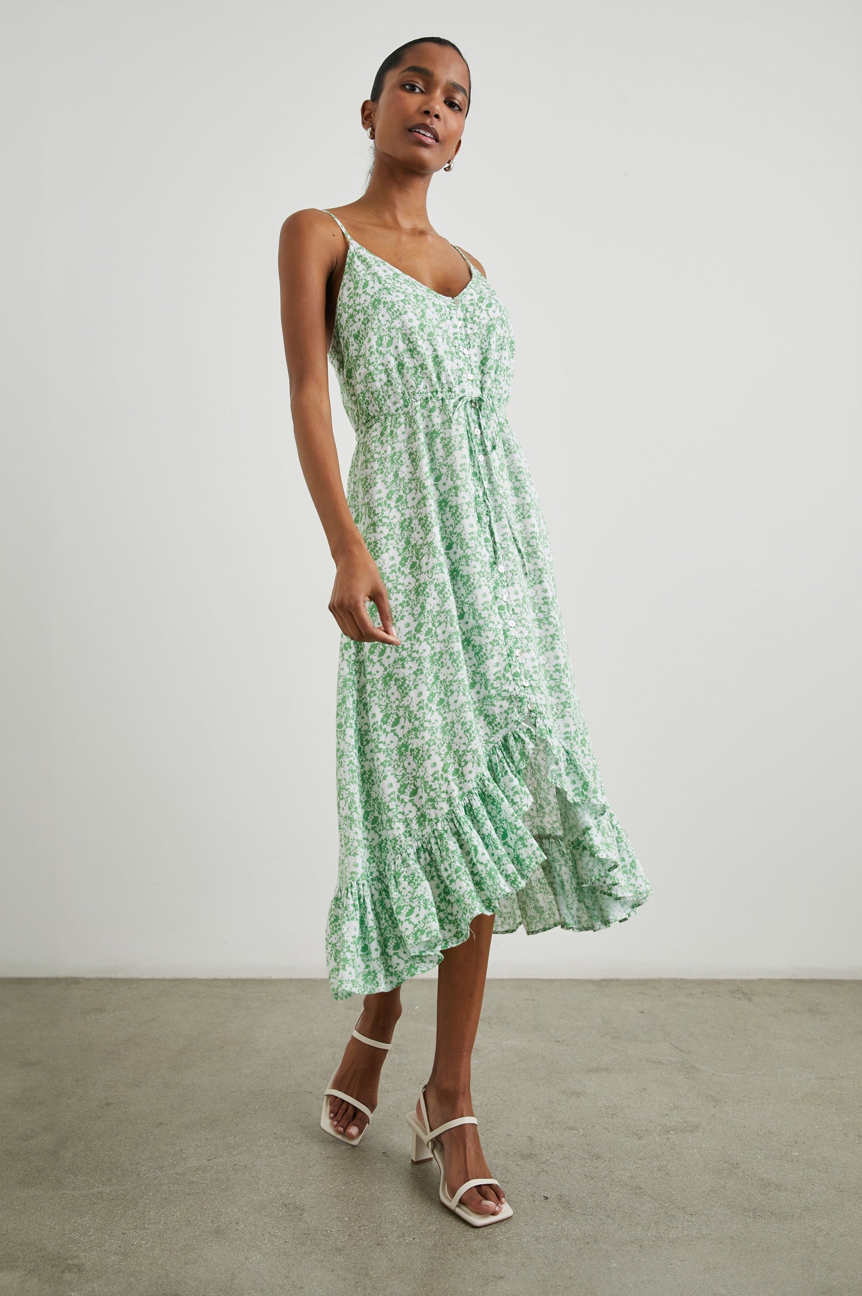 Frida Midi Dress with a Deep V Neck, Adjustable Spaghetti Straps, a Ruffled Hem, Drawstring Waist Ties and Buttons Down the Front in Green Texture Floral Colorway, Green and White Flowers - Side Full Body View Featured on Model