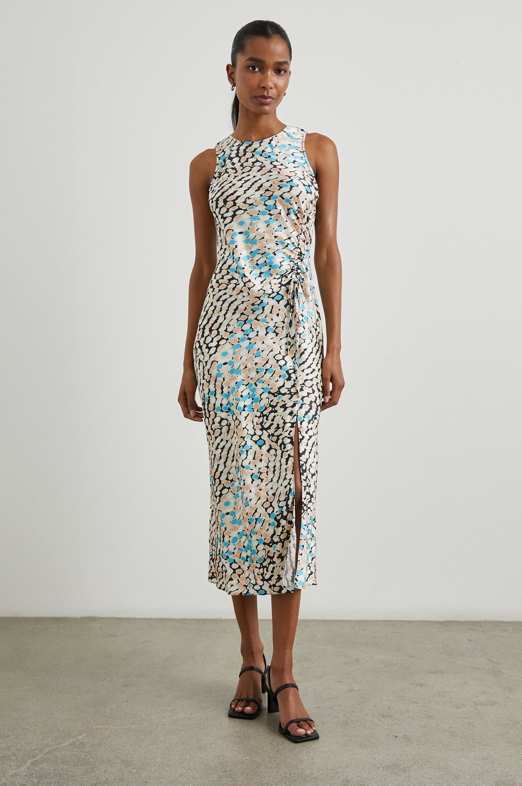 Gabriella Sleeveless Midi Dress with a Crew Neck, a Left Thigh Side Slit, a Ruched Drawstring on the Left Side and a Keyhole Button Closure at the Back in Andorra Colorway, Ovals in Blue, Browns and Cream on Black - Front Full Body View Featured on Model