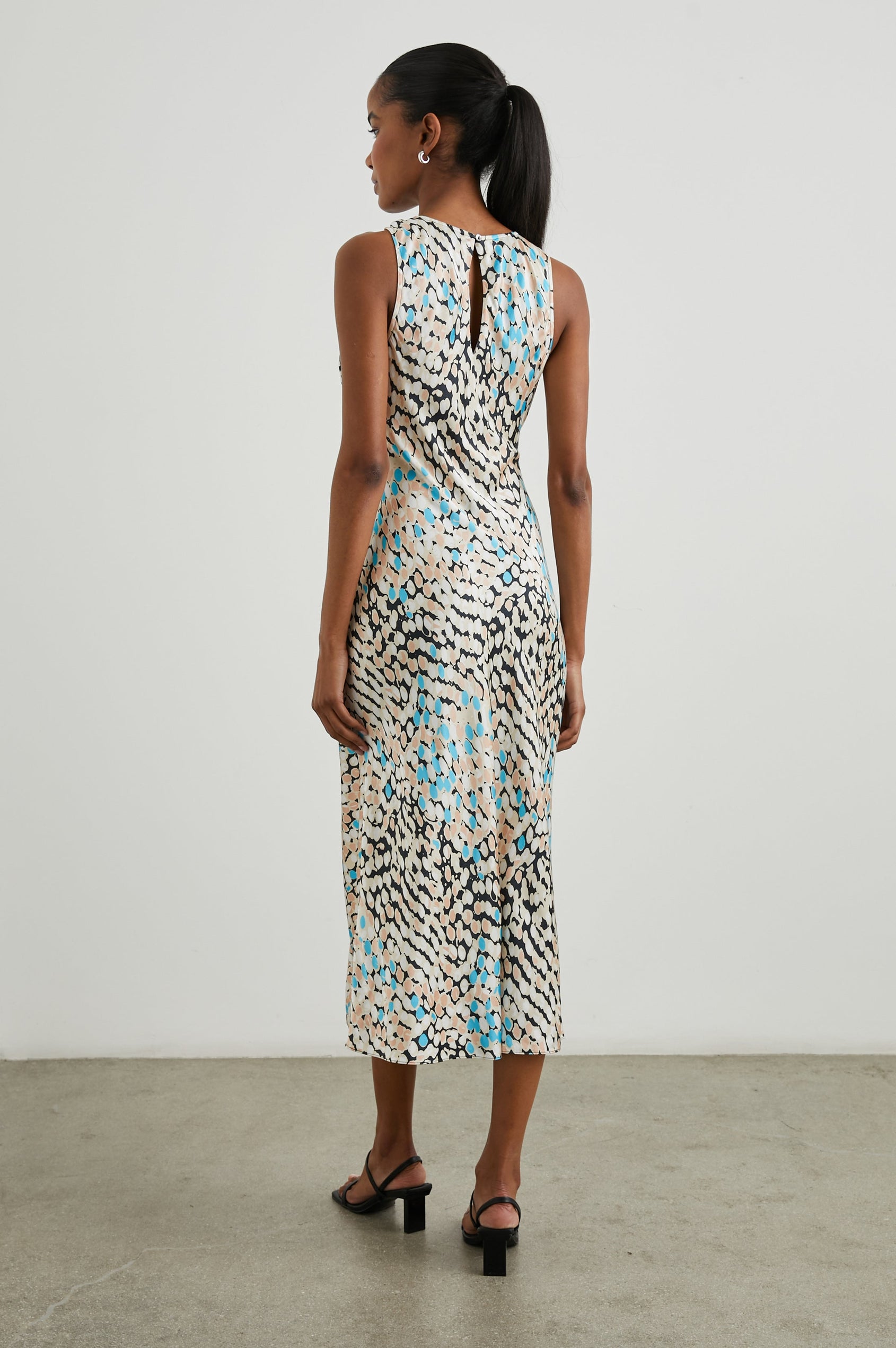 Gabriella Sleeveless Midi Dress with a Crew Neck, a Left Thigh Side Slit, a Ruched Drawstring on the Left Side and a Keyhole Button Closure at the Back in Andorra Colorway, Ovals in Blue, Browns and Cream on Black - Back Full Body View Featured on Model