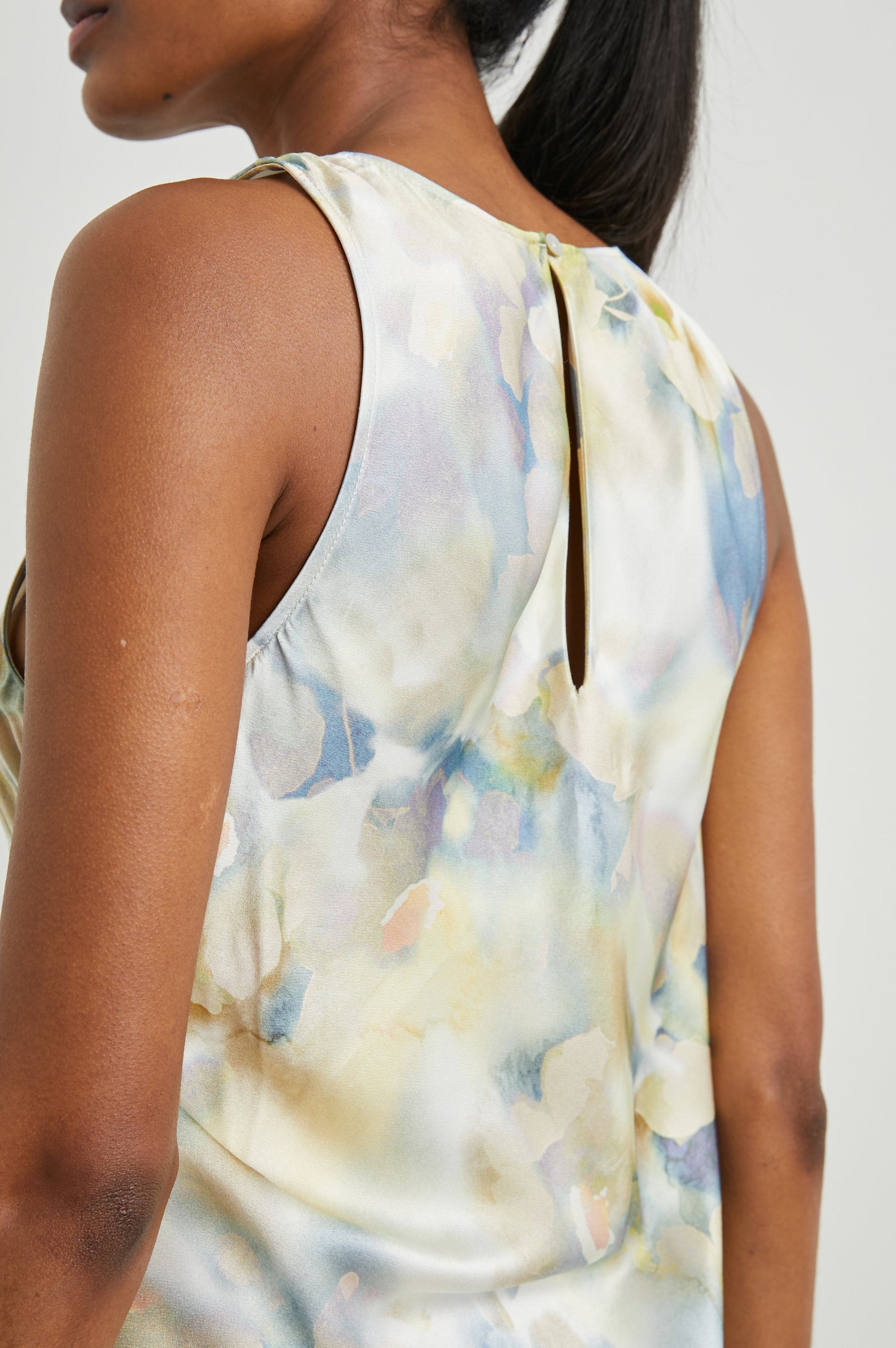 Gabriella Sleeveless Midi Dress with a Crew Neck, a Left Thigh Side Slit, a Ruched Drawstring on the Left Side and a Keyhole Button Closure at the Back in Diffused Blossom Colorway, Flowers in Golds, Creams and Blues on White - Back View Featured on Model