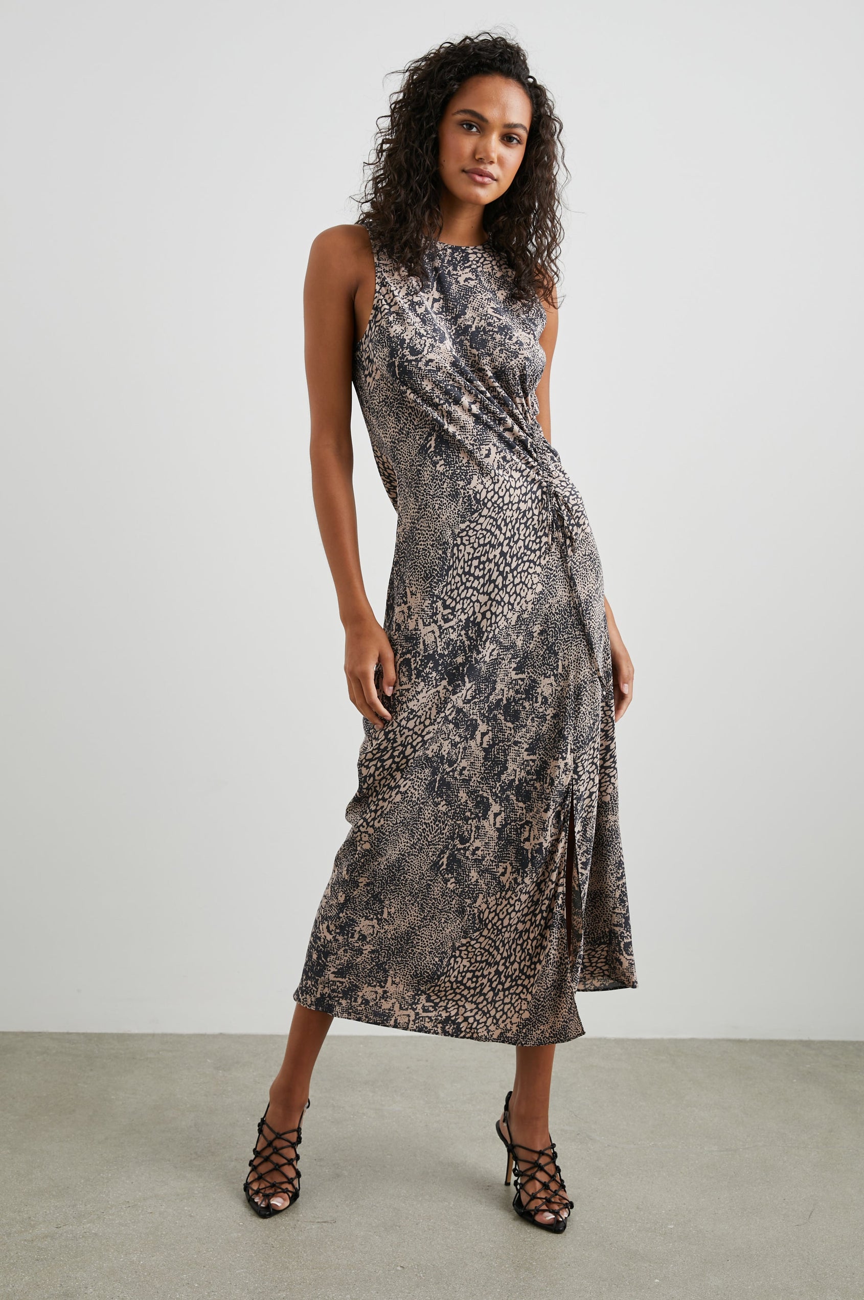 Gabriella Sleeveless Midi Dress with a Crew Neck, a Left Thigh Side Slit, a Ruched Drawstring on the Left Side and a Keyhole Button Closure at the Back in Taupe Mixed Animal Colorway, Mixed Black Spot Patterns on Taupe - Front Full Body View Featured on Model