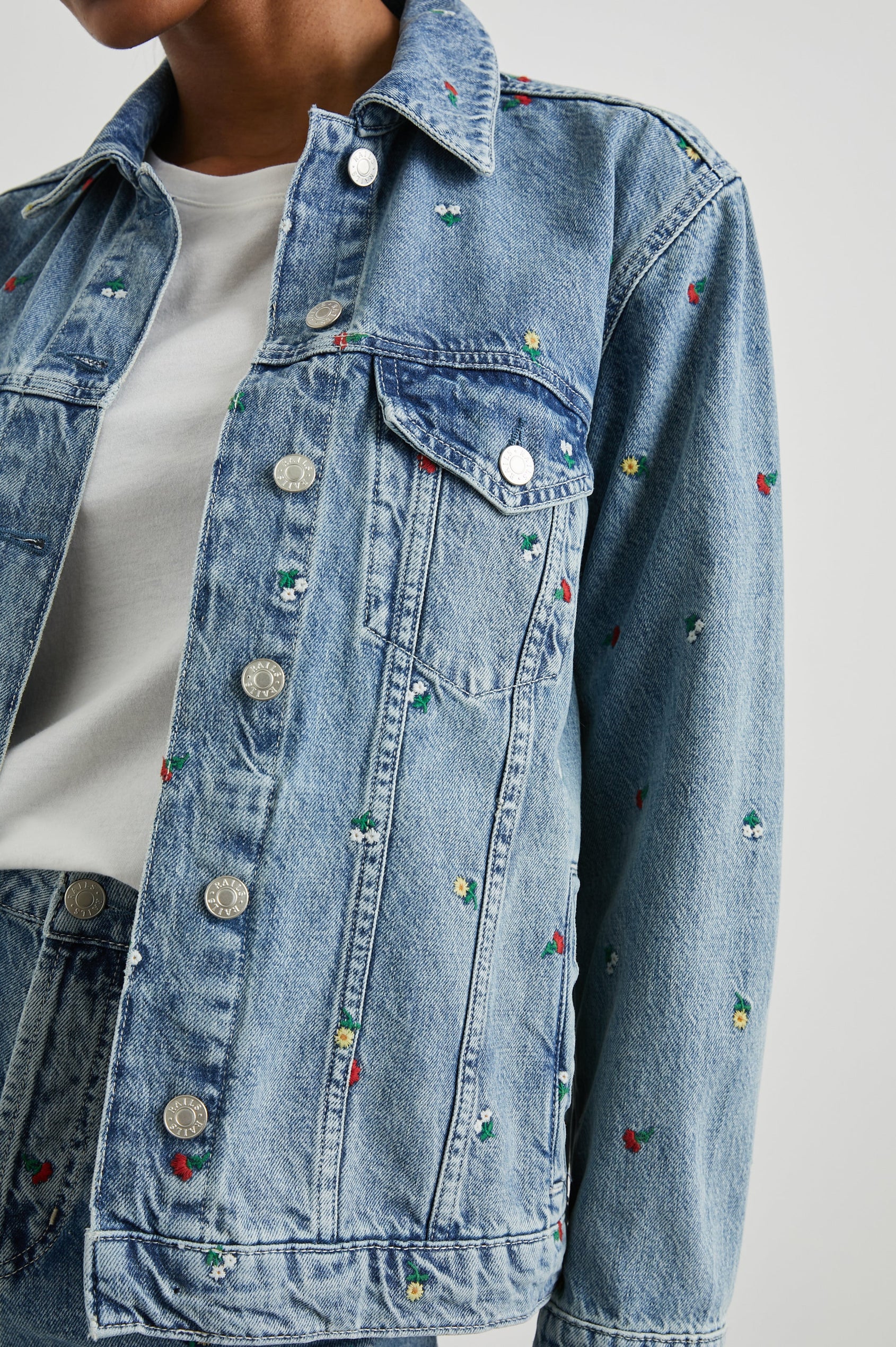 Grove Boyfriend Trucker Denim Jacket with Button Closure, Two Front Pockets, Two Chest Button Flap Pockets, Front Vertical Seams in Flower Field Colorway, with Embroidered Daisies in Yellow, Red and White - Front View Featured on Model
