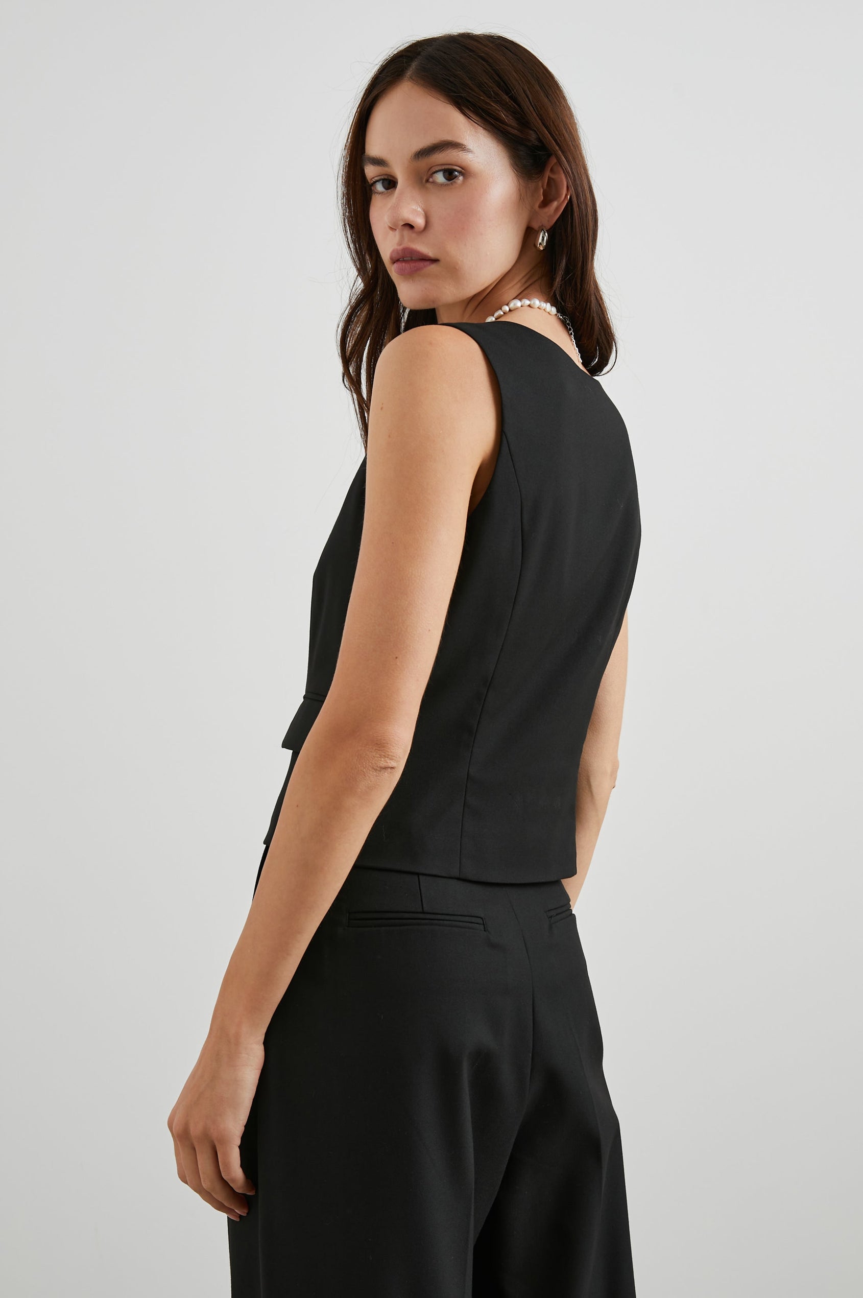 Guilia Cropped Vest with a Square Neckline, Button Closure and Two Front Flap Pockets in Black Twill Colorway - Back View Featured on Model