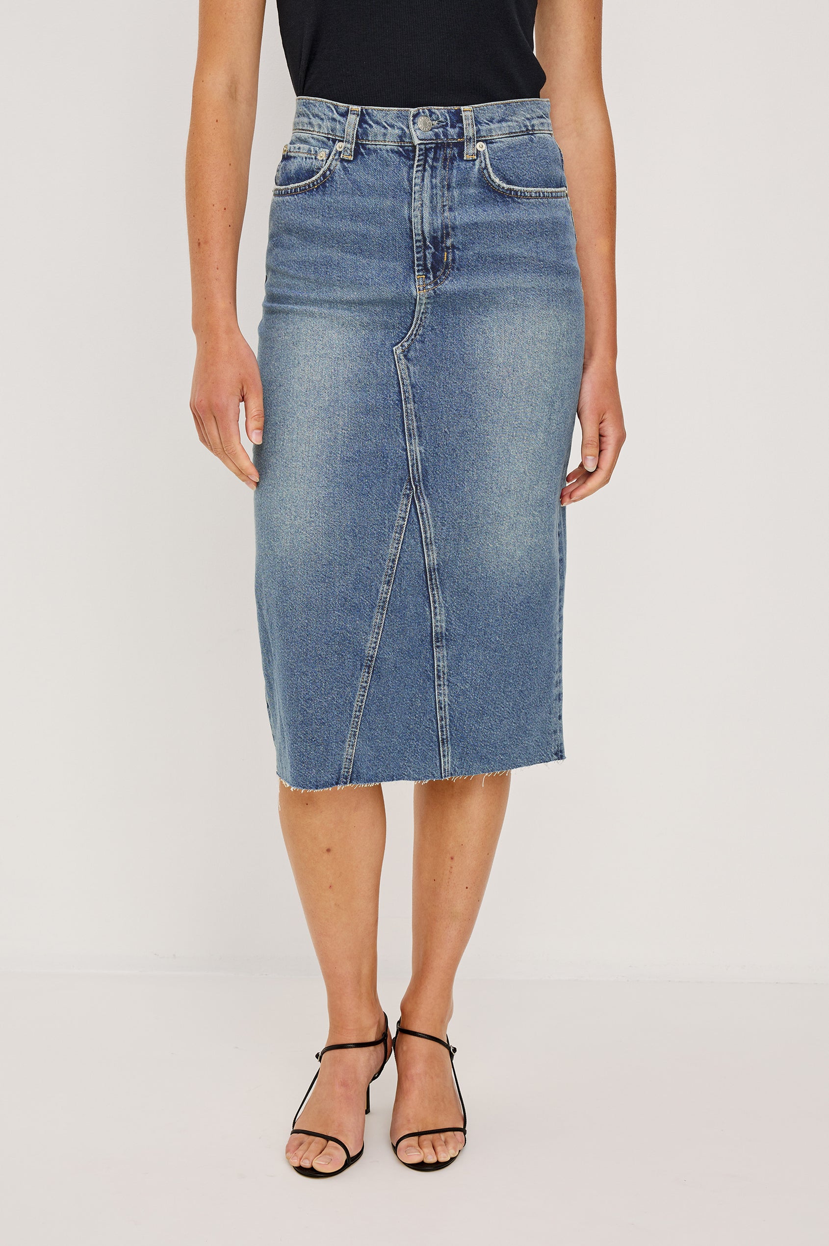Highland Denim Midi Skirt with a Raw Hem, a Back Vent, Additional Front Seams, Belt Loops, Two Front Pockets plus a Coin Pocket and Two Back Patch Pockets in Vintage Sapphire Colorway - Front View Featured on Model