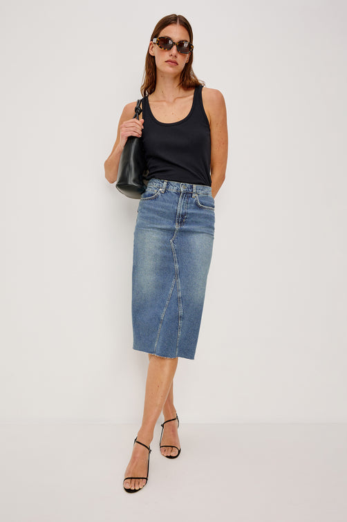 Highland Denim Midi Skirt with a Raw Hem, a Back Vent, Additional Front Seams, Belt Loops, Two Front Pockets plus a Coin Pocket and Two Back Patch Pockets in Vintage Sapphire Colorway - Front Full Body View Featured on Model