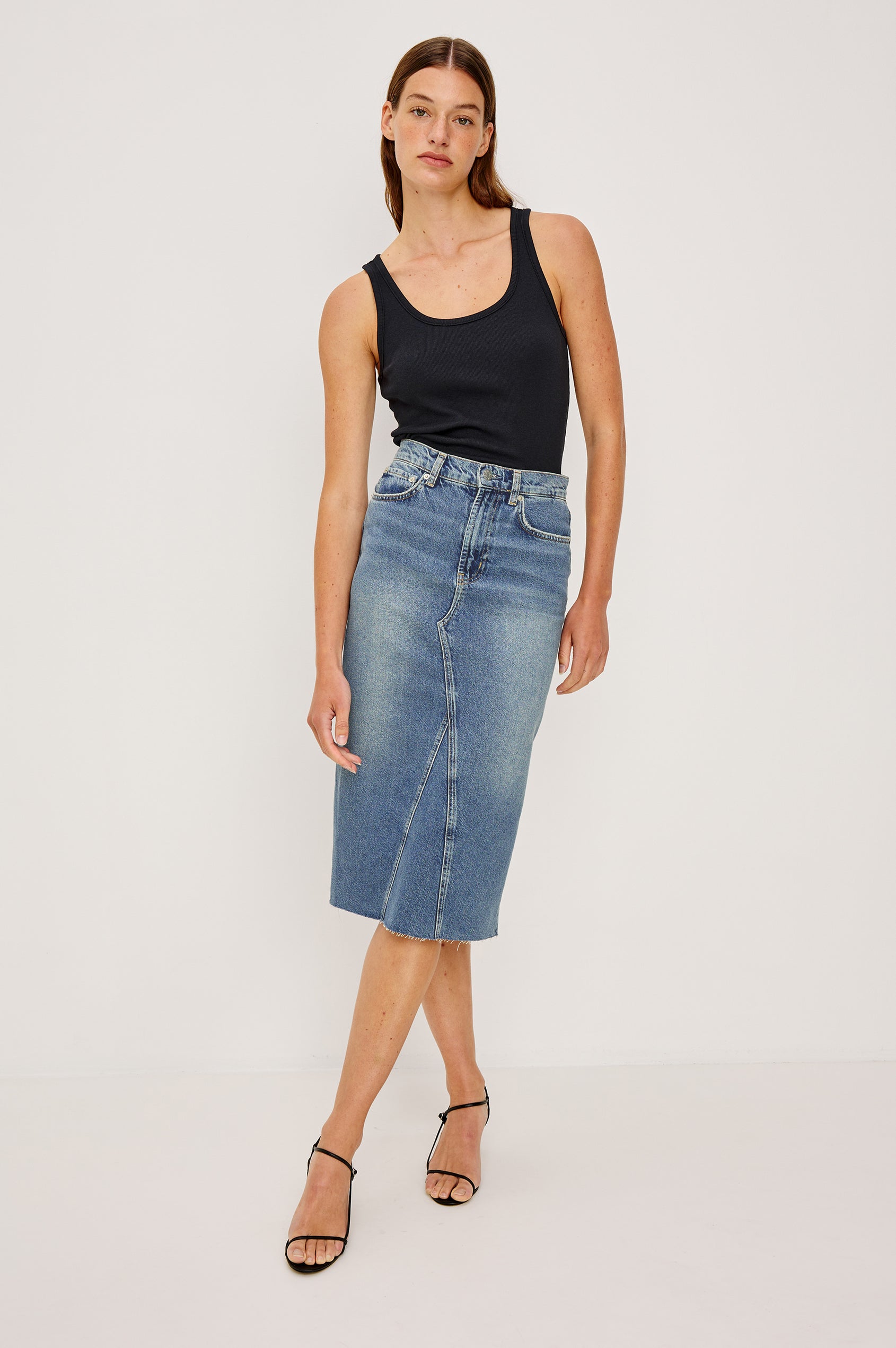 Highland Denim Midi Skirt with a Raw Hem, a Back Vent, Additional Front Seams, Belt Loops, Two Front Pockets plus a Coin Pocket and Two Back Patch Pockets in Vintage Sapphire Colorway - Front Full Body View Featured on Model