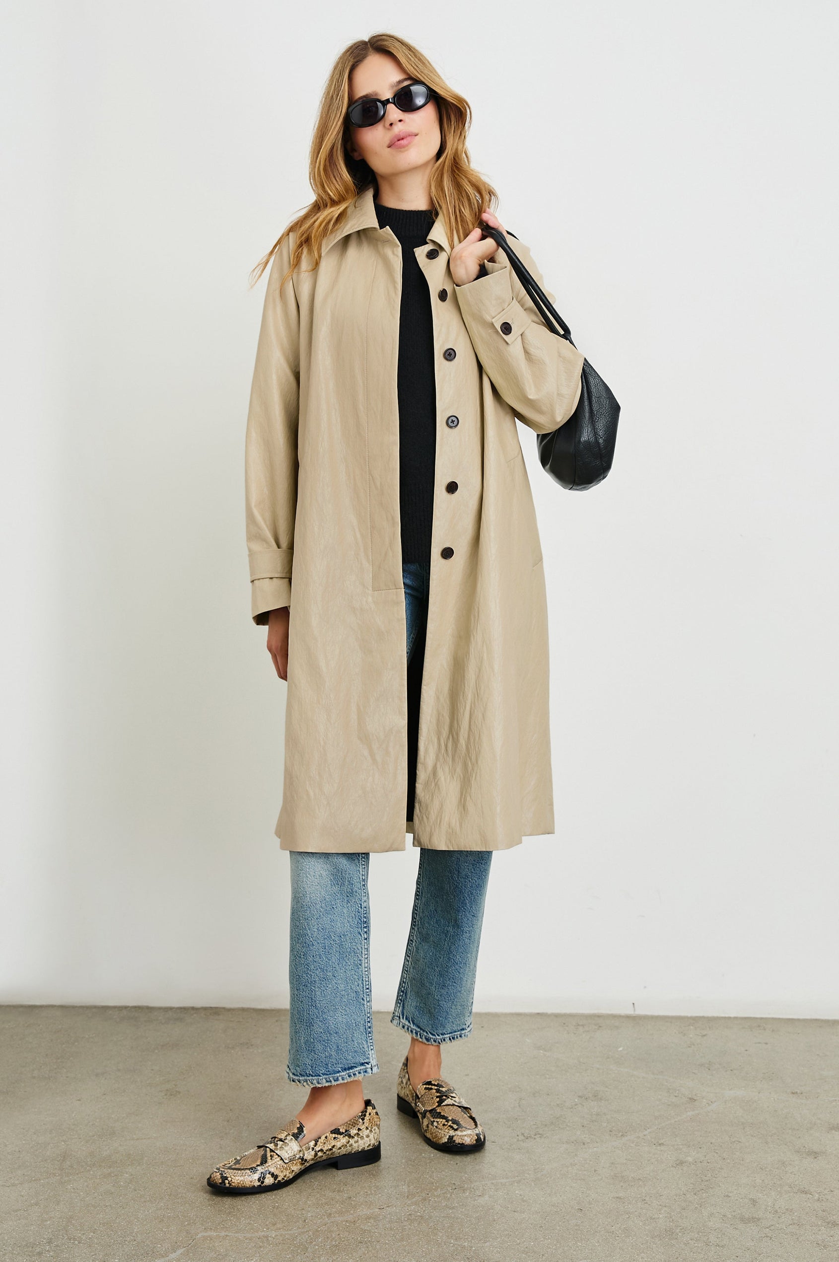 Hills Knee-Length Faux Leather Jacket with Button Closure, a Hidden Placket, Two Front Pockets, and Button Tabs at the Cuffs in Dune Colorway - Front Full Body View Featured on Model