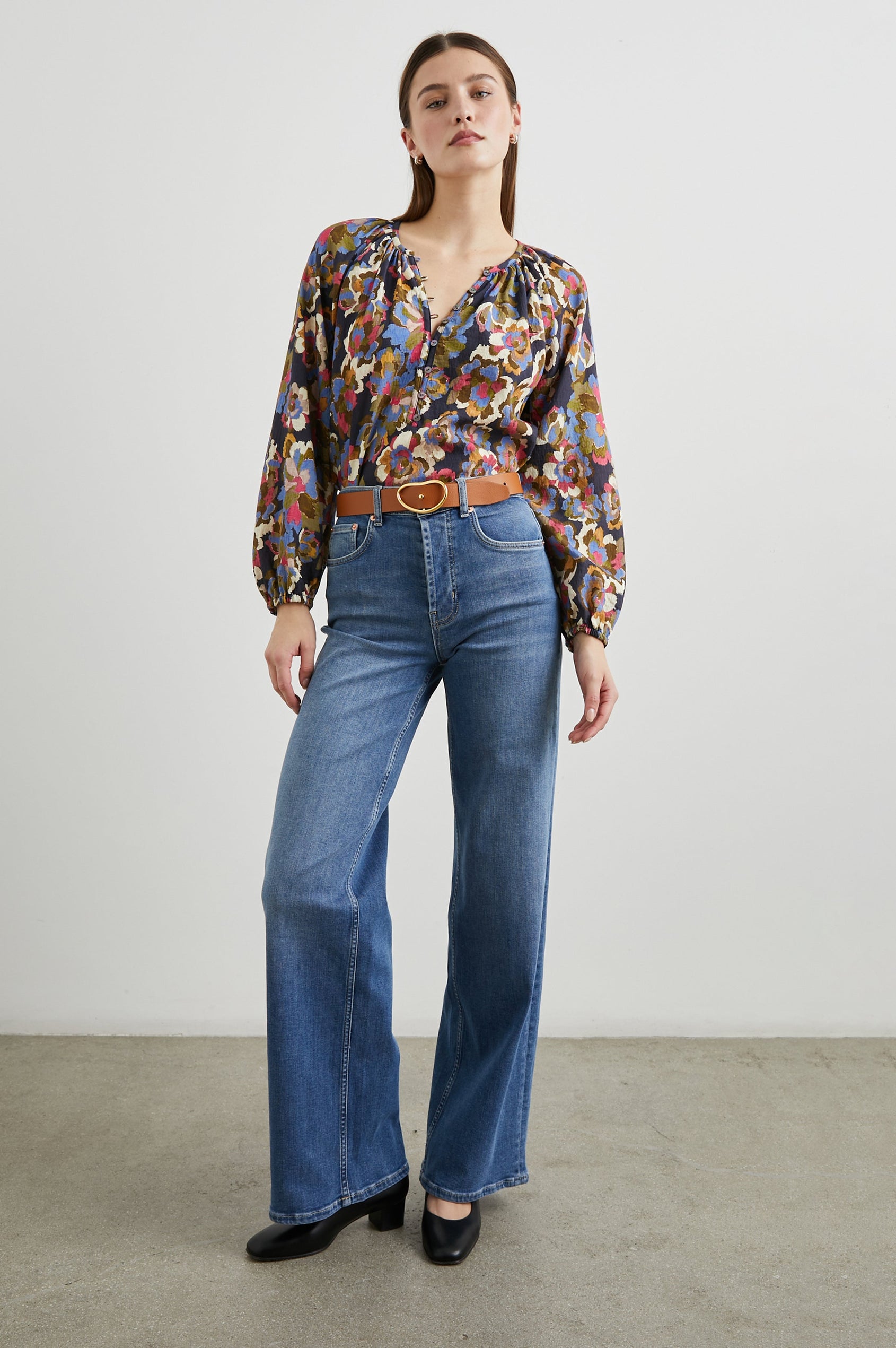 Indi Top with a V Neckline with a Button Placket, Pleating at Back Neckline and Elastic Cuffs in Navy Wildflower Colorway, with blue, gold, green and cream flowers on navy - Front tucked Full Body View Featured on Model