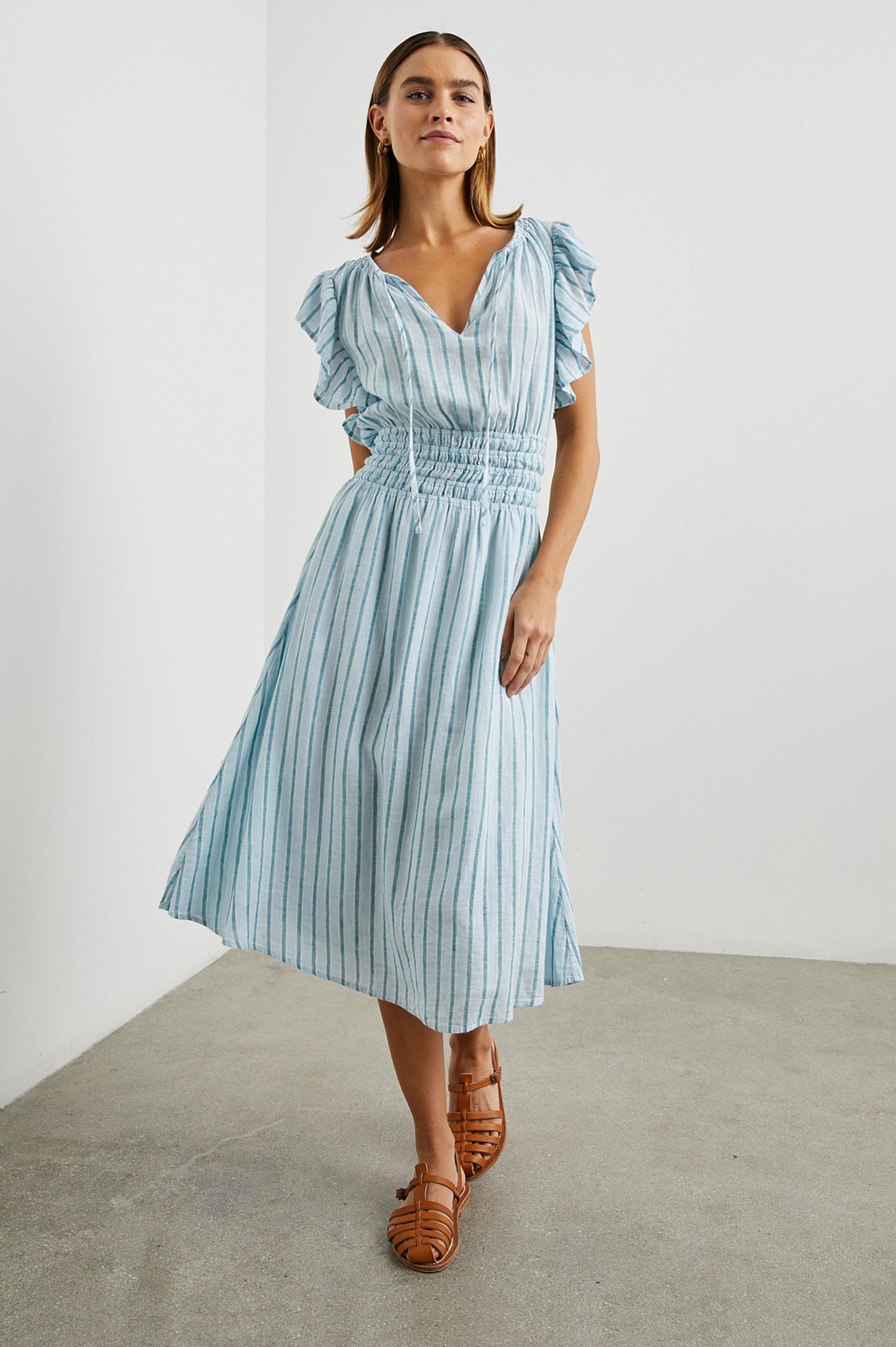 Iona Short Sleeve Midi Dress with Flutter Sleeves, a Deep V Neck with Ties, and a Shirred Waist in Cambria Stripe Colorway, Vertical Stripes in White, Blue and Light Blue - Front Full Body View Featured on Model
