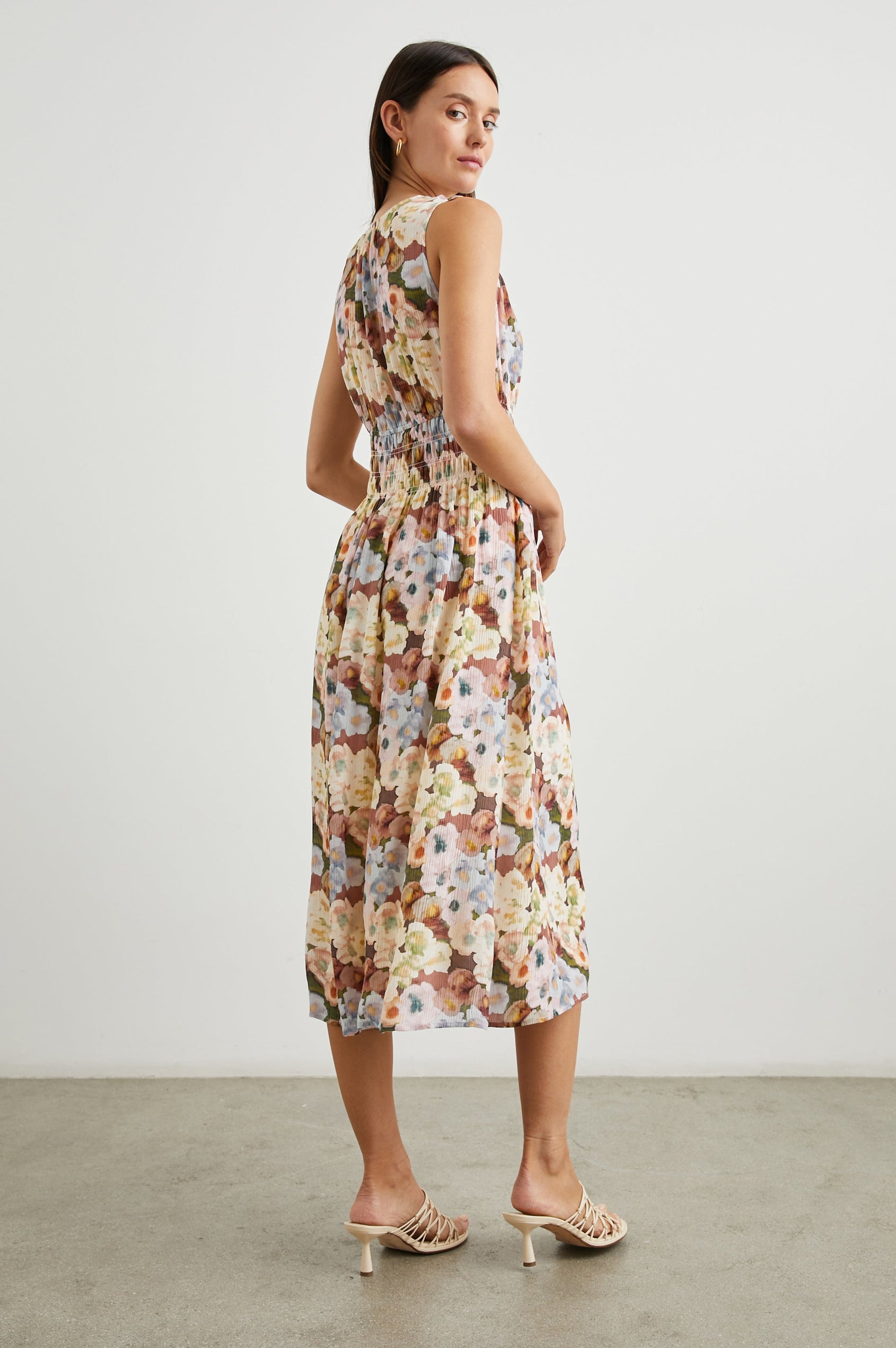 Izzy Sleeveless Midi Dress with Wide Smocked Shoulder Straps, a Smocked Waist and a Deep V Neck, in Painted Floral Colorway, in Browns, Yellows, Pinks, Blues and Greens - Back Full Body View Featured on Model