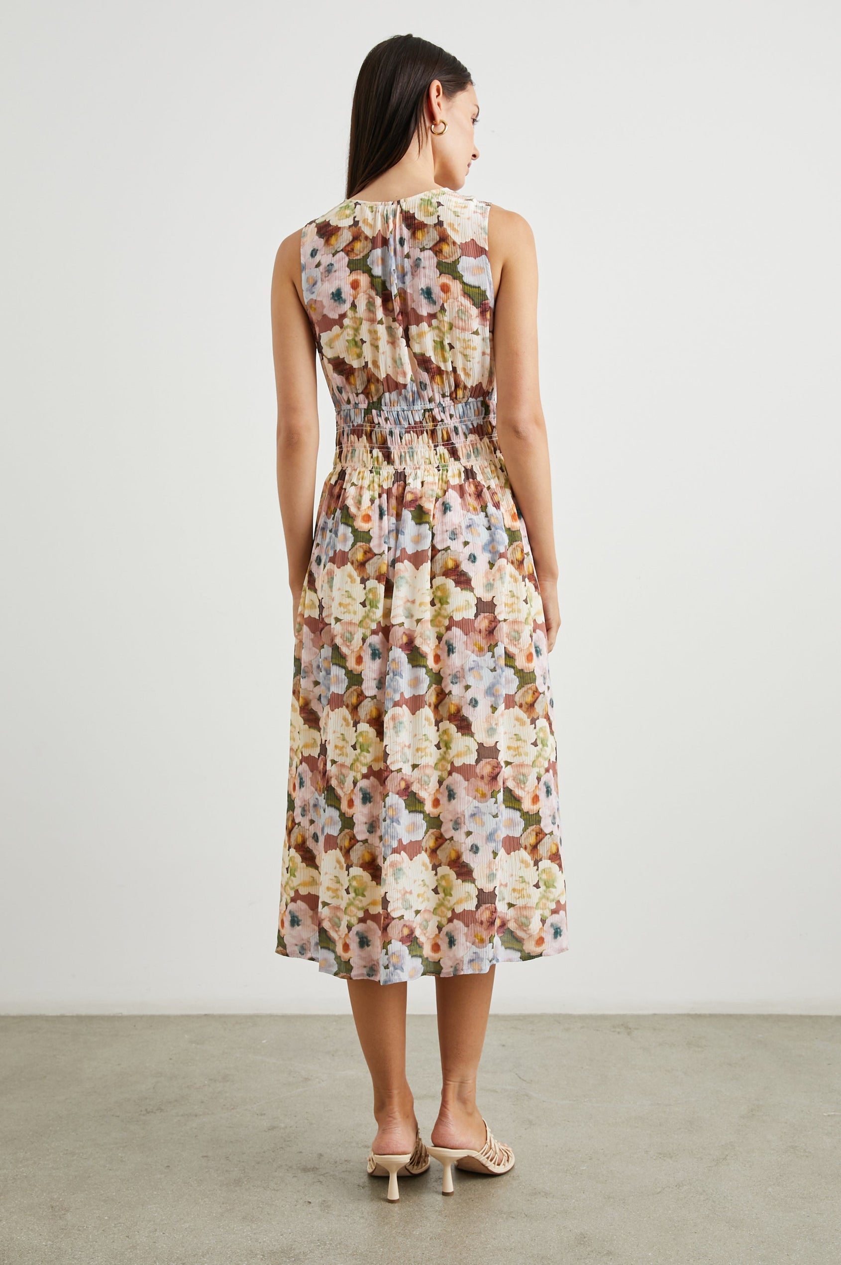 Izzy Sleeveless Midi Dress with Wide Smocked Shoulder Straps, a Smocked Waist and a Deep V Neck, in Painted Floral Colorway, in Browns, Yellows, Pinks, Blues and Greens - Back Full Body View Featured on Model