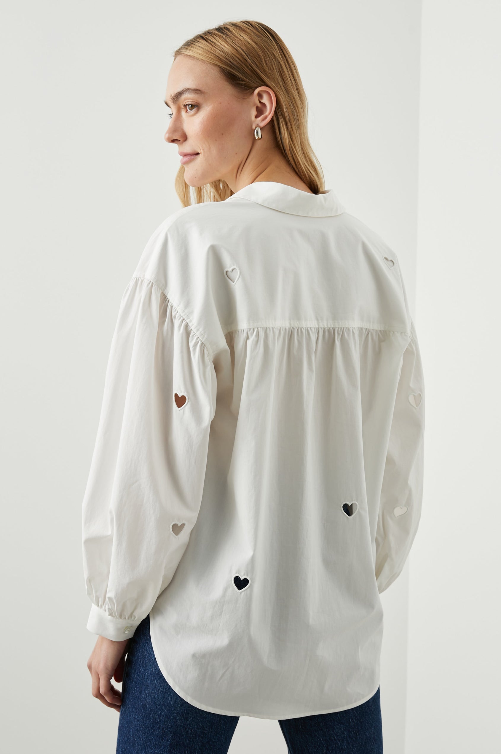 Janae Long Sleeve Button Up with a Chest Patch Pocket, Light Ruching at the Cuffs and Sleeve Shoulder and Cutout Hearts in White Eyelet Hearts Colorway - Back View Featured on Model