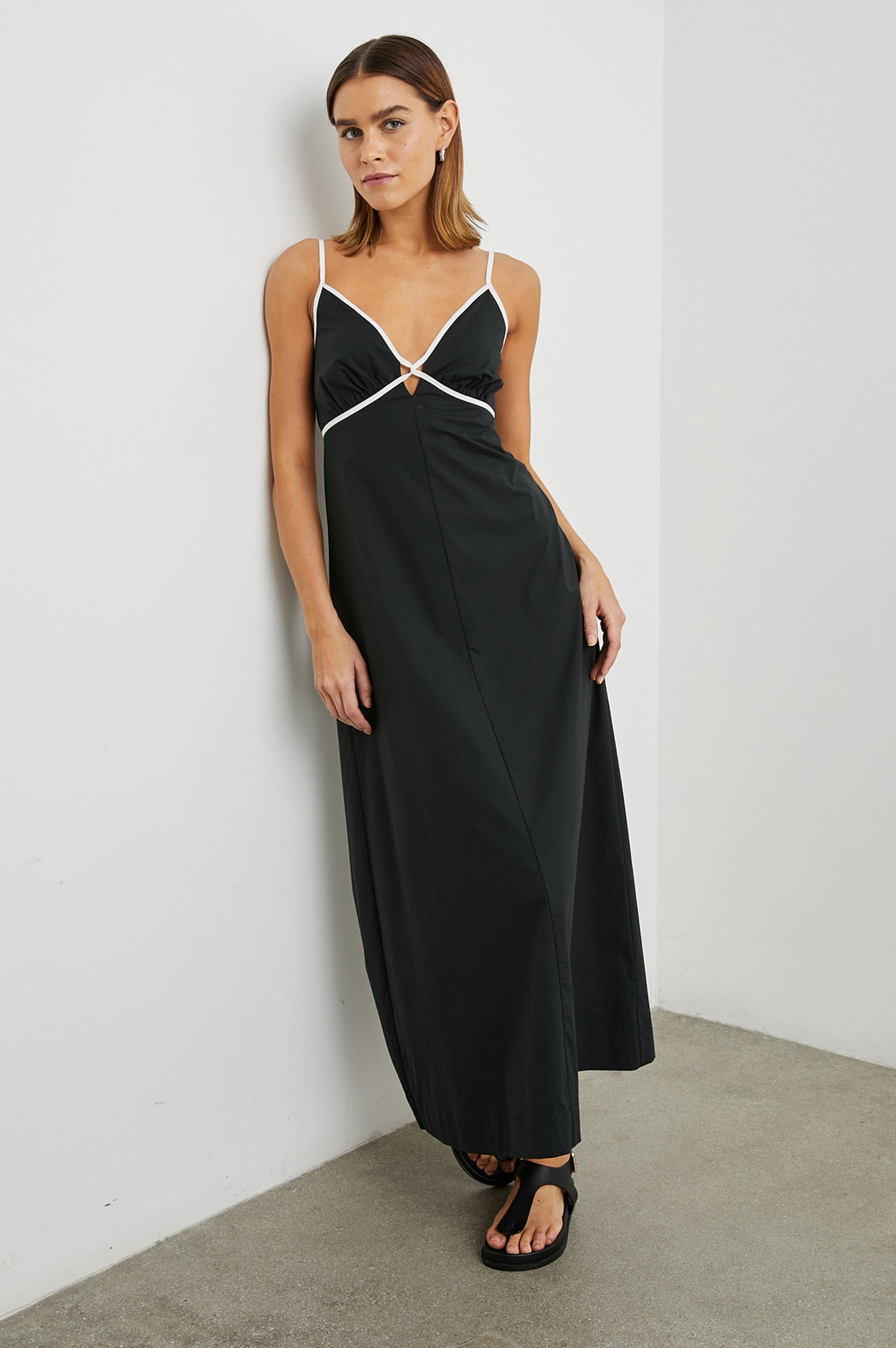 Jessa Sleeveless Maxi Dress with Adjustable Spaghetti Straps, a Deep V Neck with a Cutout, a Shirred Back and White Trim on the Bodice in Black Colorway - Front Full Body View Featured on Model