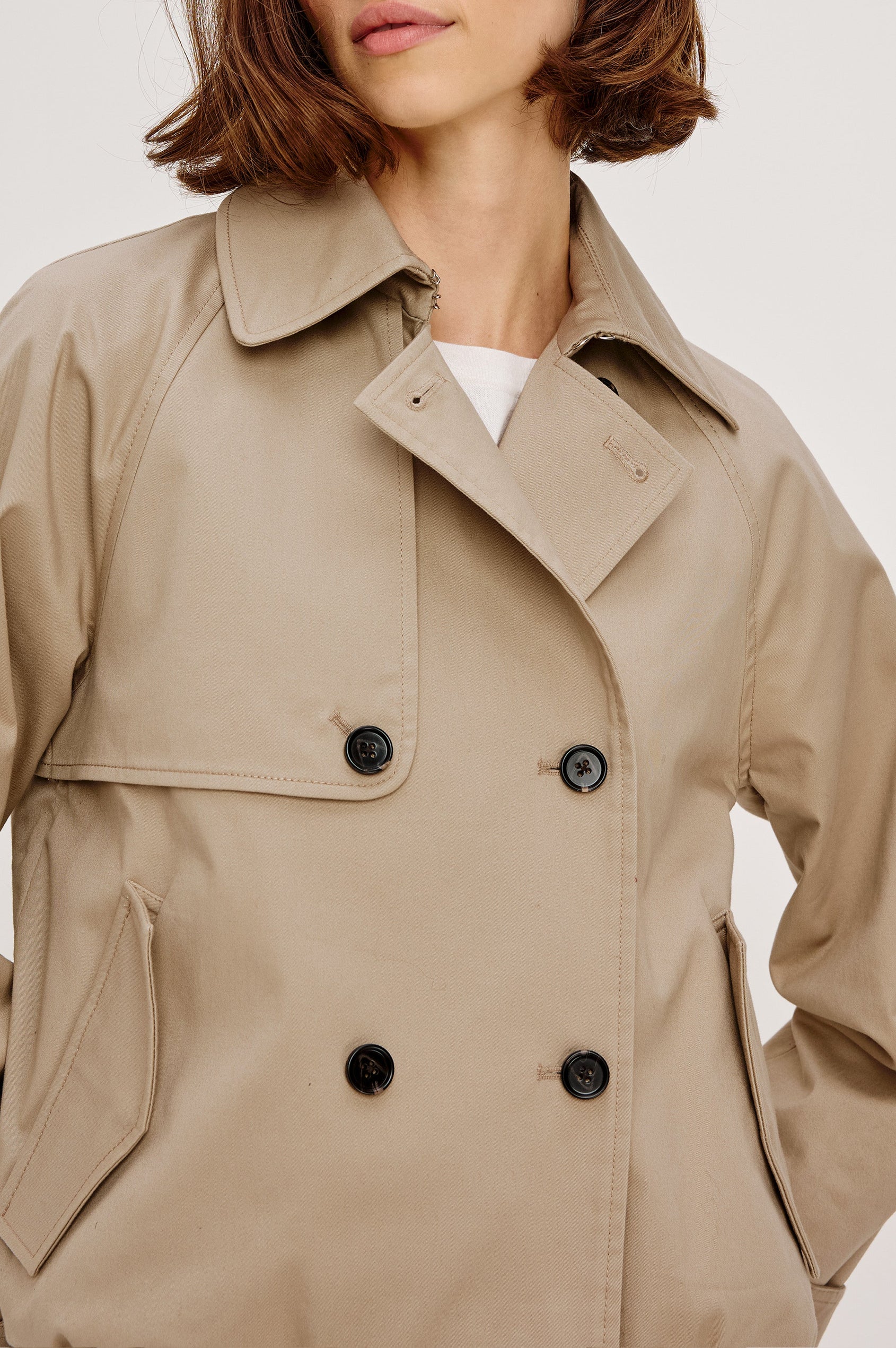 Jett Double Breasted, Cropped Trench Jacket, Lapel, Adjustable Cuff Belt, Side Pockets and Elasticated Hem in Taupe Colorway. Front Detail View Featured on Model.