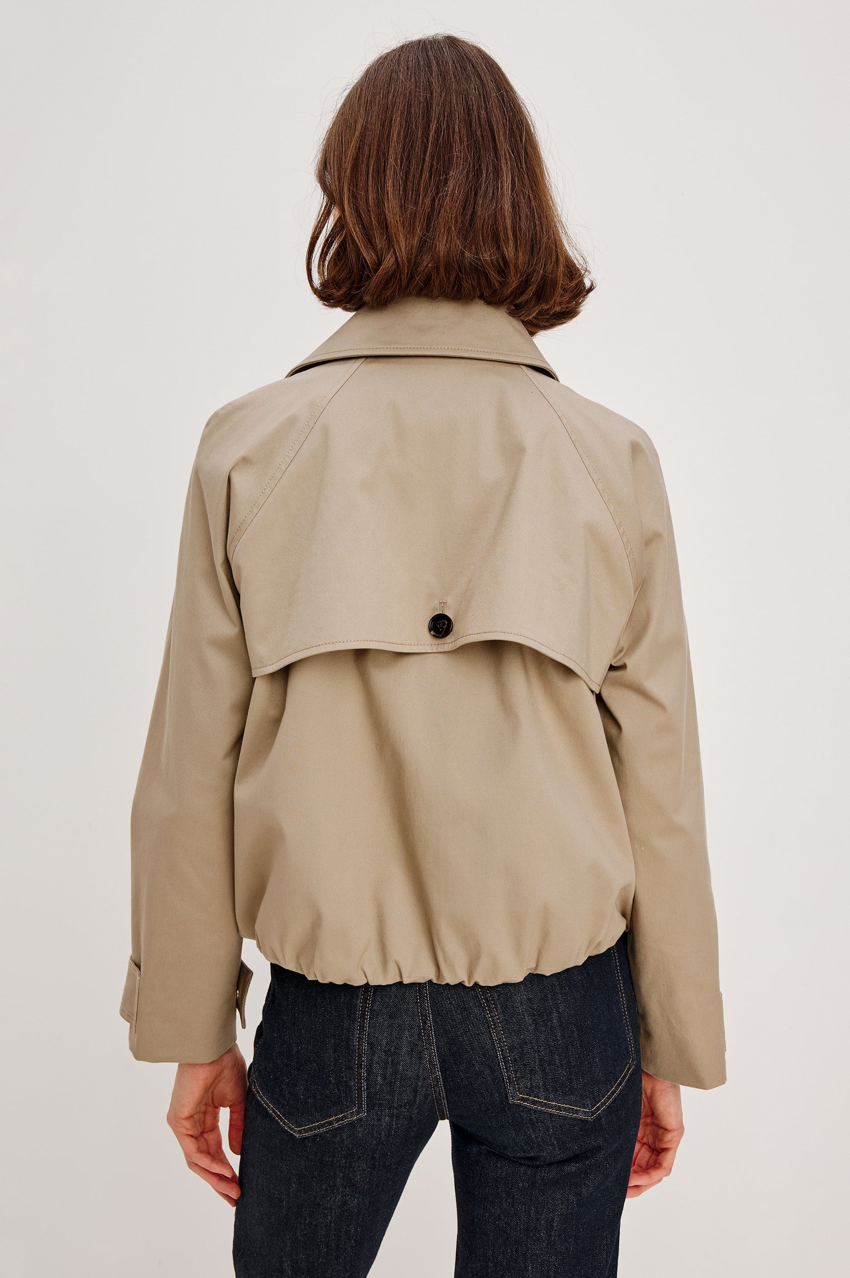 Jett Double Breasted, Cropped Trench Jacket, Lapel, Adjustable Cuff Belt, Side Pockets and Elasticated Hem in Taupe Colorway. Back View Featured on Model.