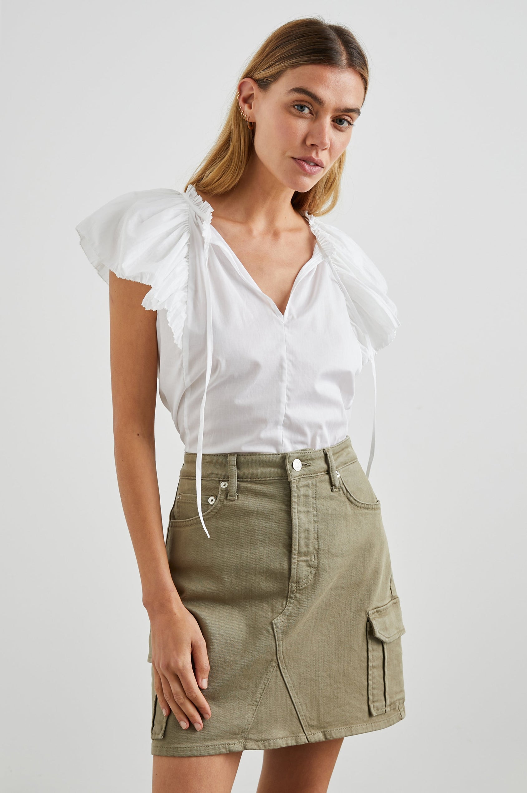 Karysa Short-Sleeve Top with Flutter Sleeves, a Deep V Neck with a Drawstring, Ruching at the Back Collar, and a Vertical Front Center Seam in White Colorway - Front Tucked Full Body View Featured on Model