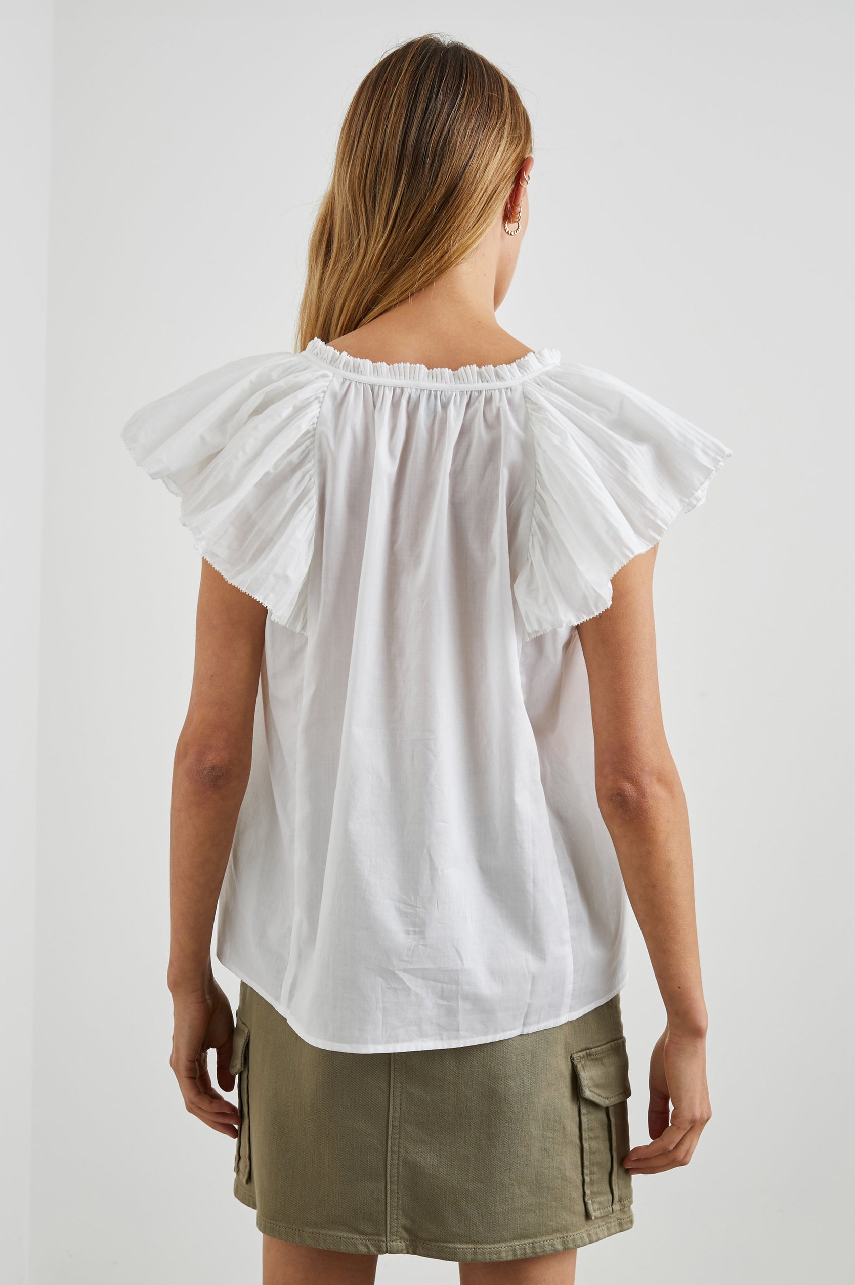 Karysa Short-Sleeve Top with Flutter Sleeves, a Deep V Neck with a Drawstring, Ruching at the Back Collar, and a Vertical Front Center Seam in White Colorway - Back View Featured on Model
