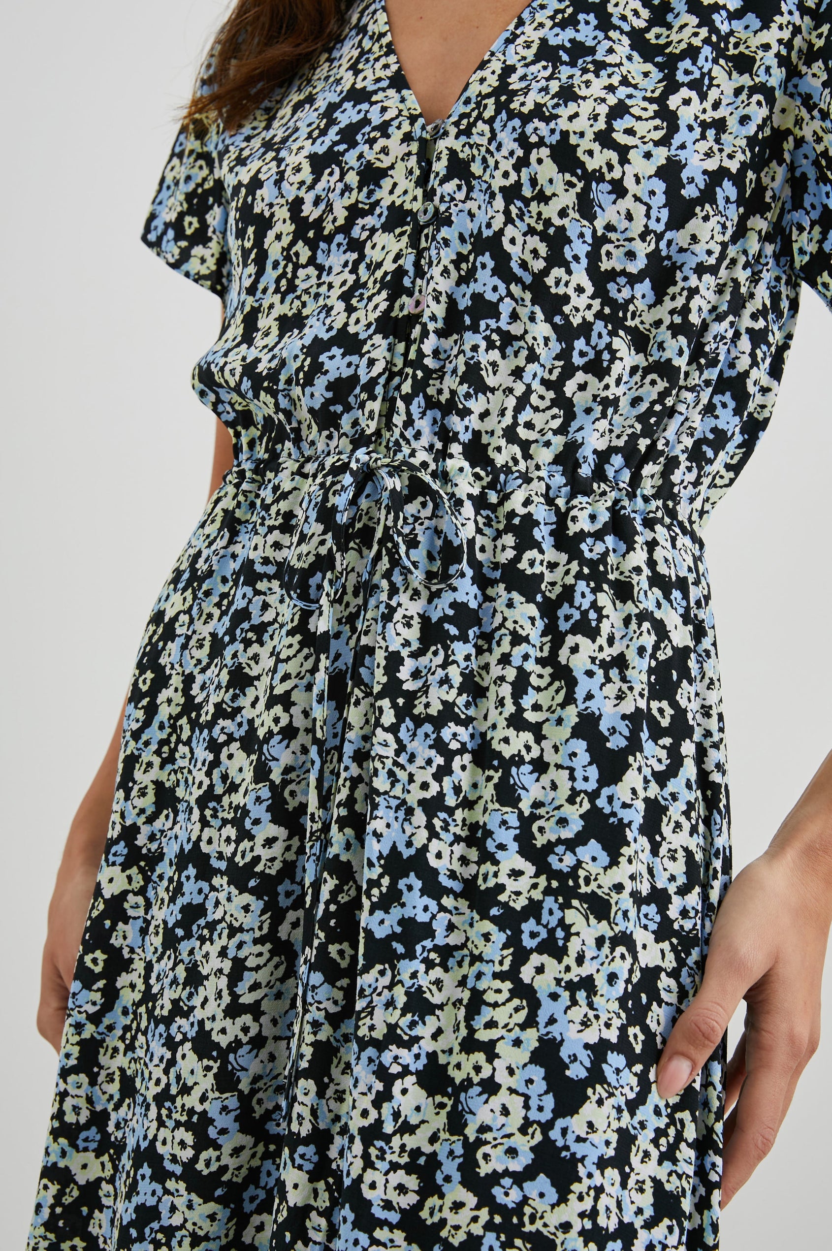 Kiki Short Sleeve Midi Dress with a V Neck, Buttons Down the Front Bodice, a Drawstring Waist and Ruffles at the Hem in Midnight Meadow Floral Colorway, Blue and Cream Flowers on Black - Front View Featured on Model
