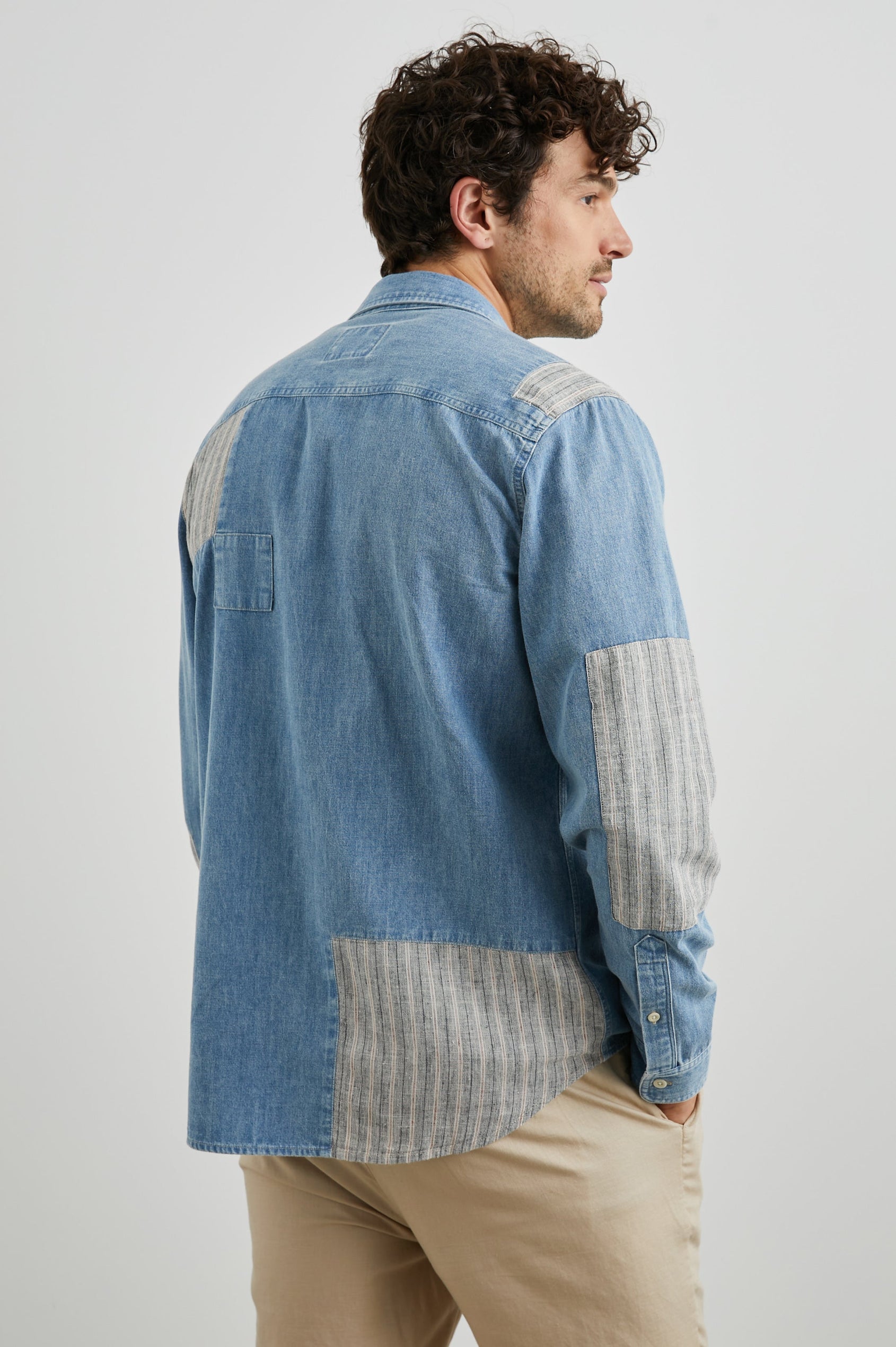 Larsen Long-Sleeve Button Up with Two Chest Button Flap Pockets in Medium Indigo Patchwork Colorway, Denim Patches and Vertical Stripes in Grey and White - Back View Featured on Model