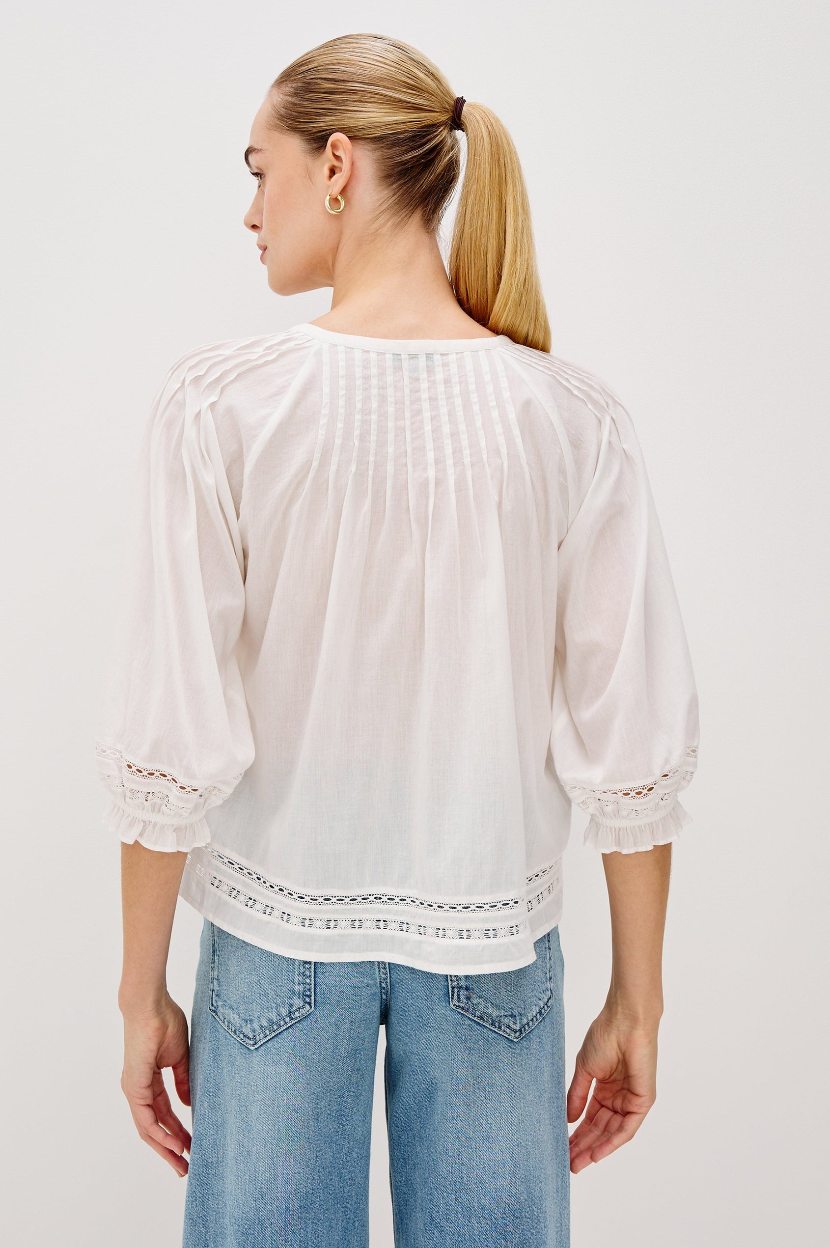 Lilah Blouse with Elbow Length Sleeves, Elastic and Gathering at Sleeve Hem, V-Neck and 3-button Front, White Lace Details at Hems in White Colorway. Back View Shown on Model.